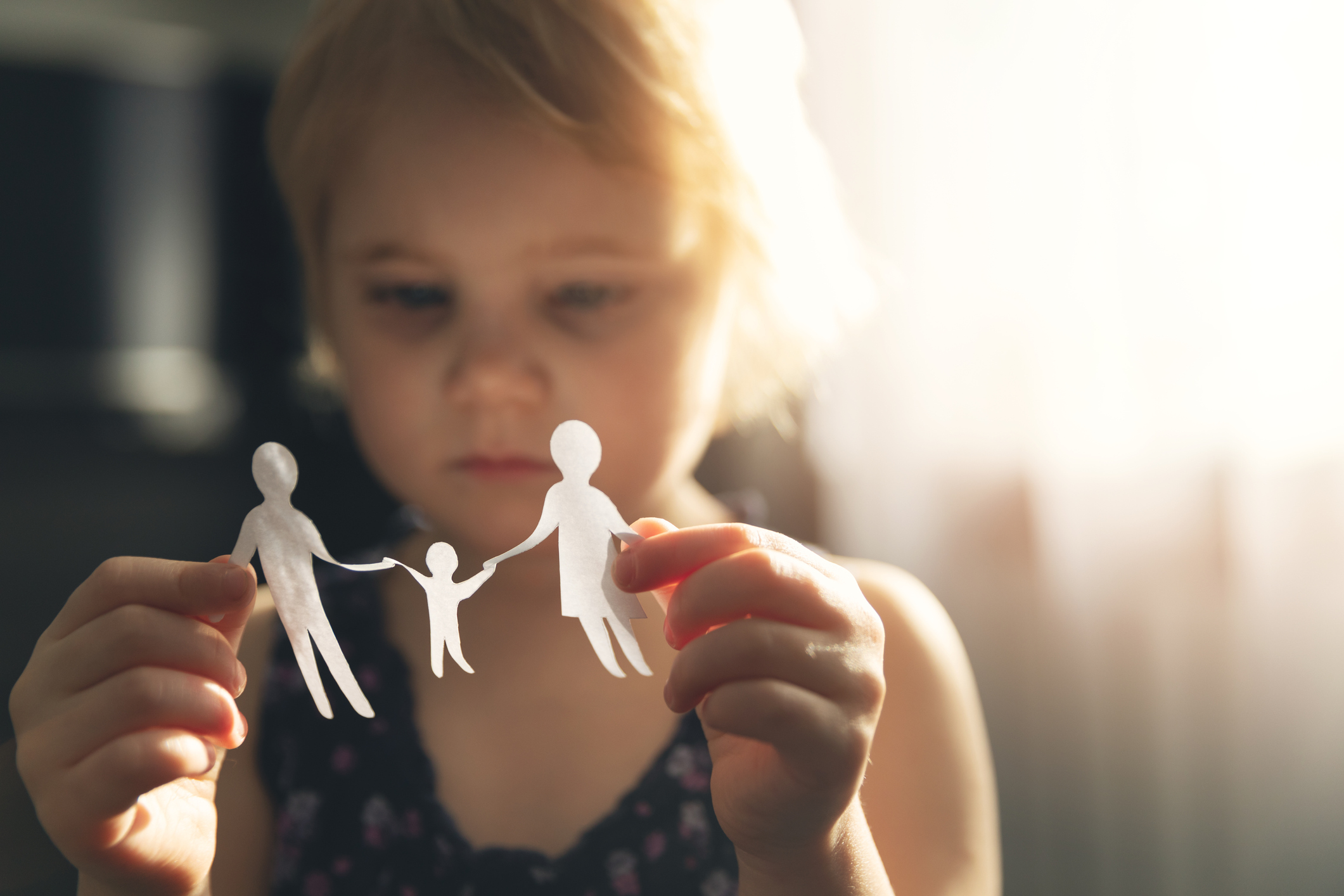 little girl with paper family in hands. concept of divorce, custody and child abuse