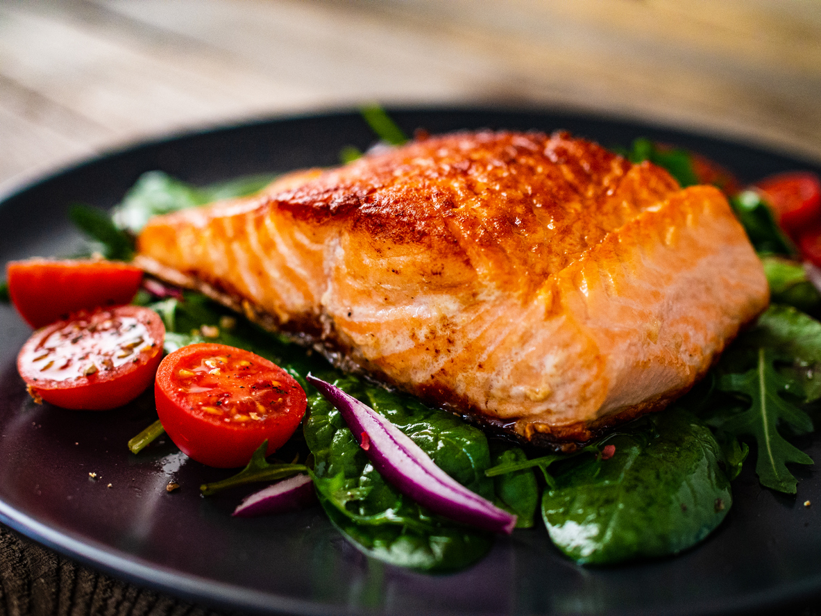 Fried salmon and vegetables on wooden background