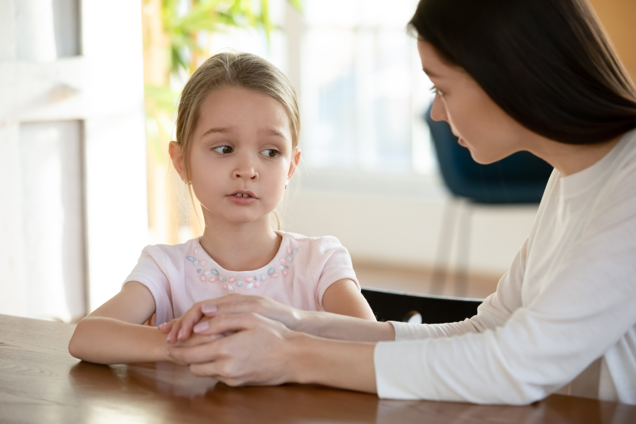 Unhappy small child girl sharing school problems with mom.