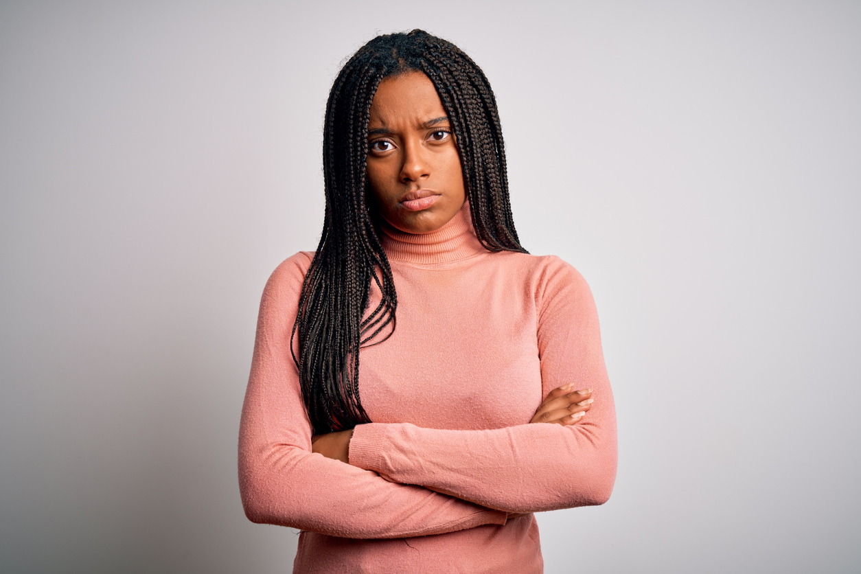 Young african american woman standing casual and cool over white isolated background skeptic and nervous, disapproving expression on face with crossed arms. Negative person.