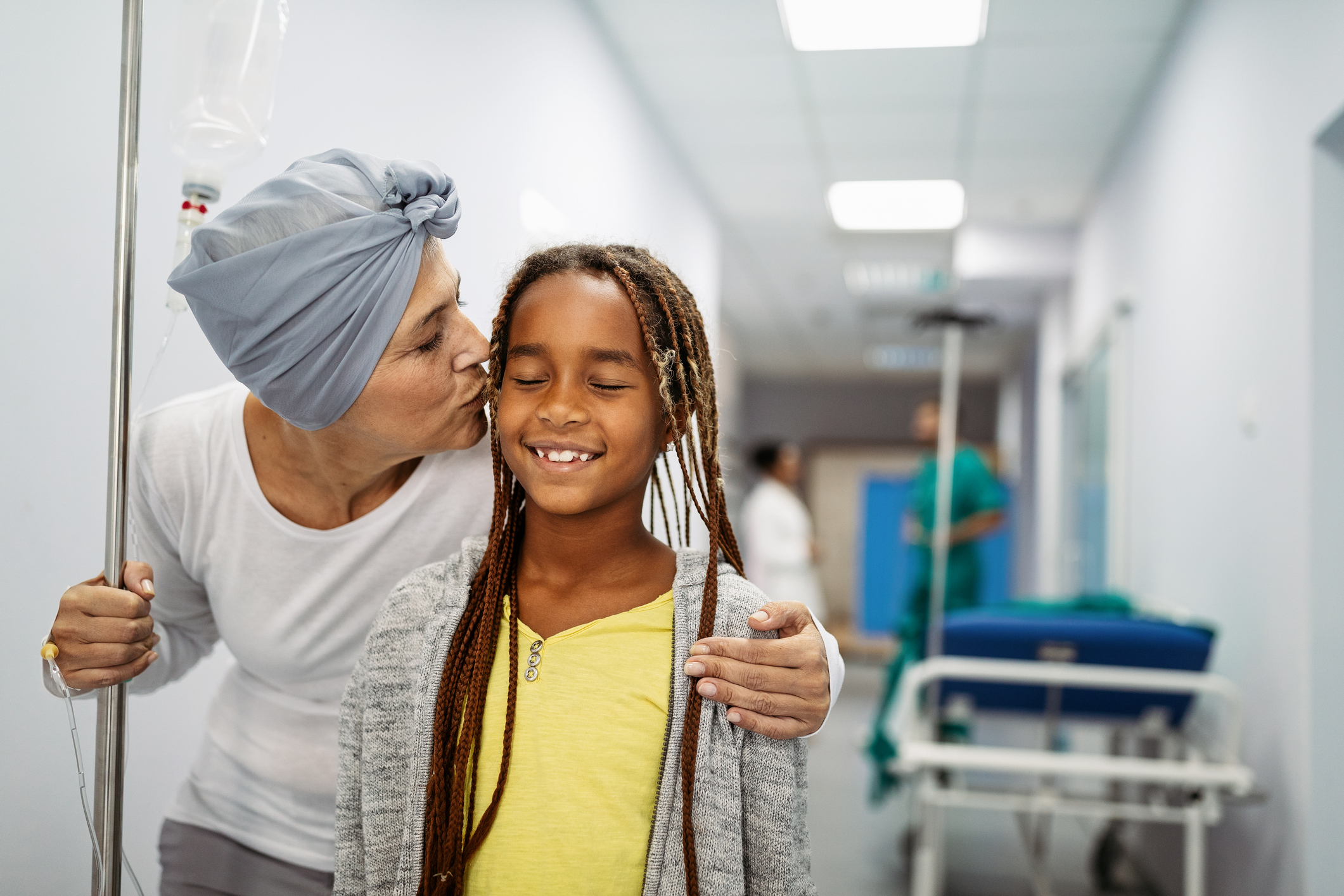 Sick woman with cancer hugging her young grandchild in hospital. Family support concept.