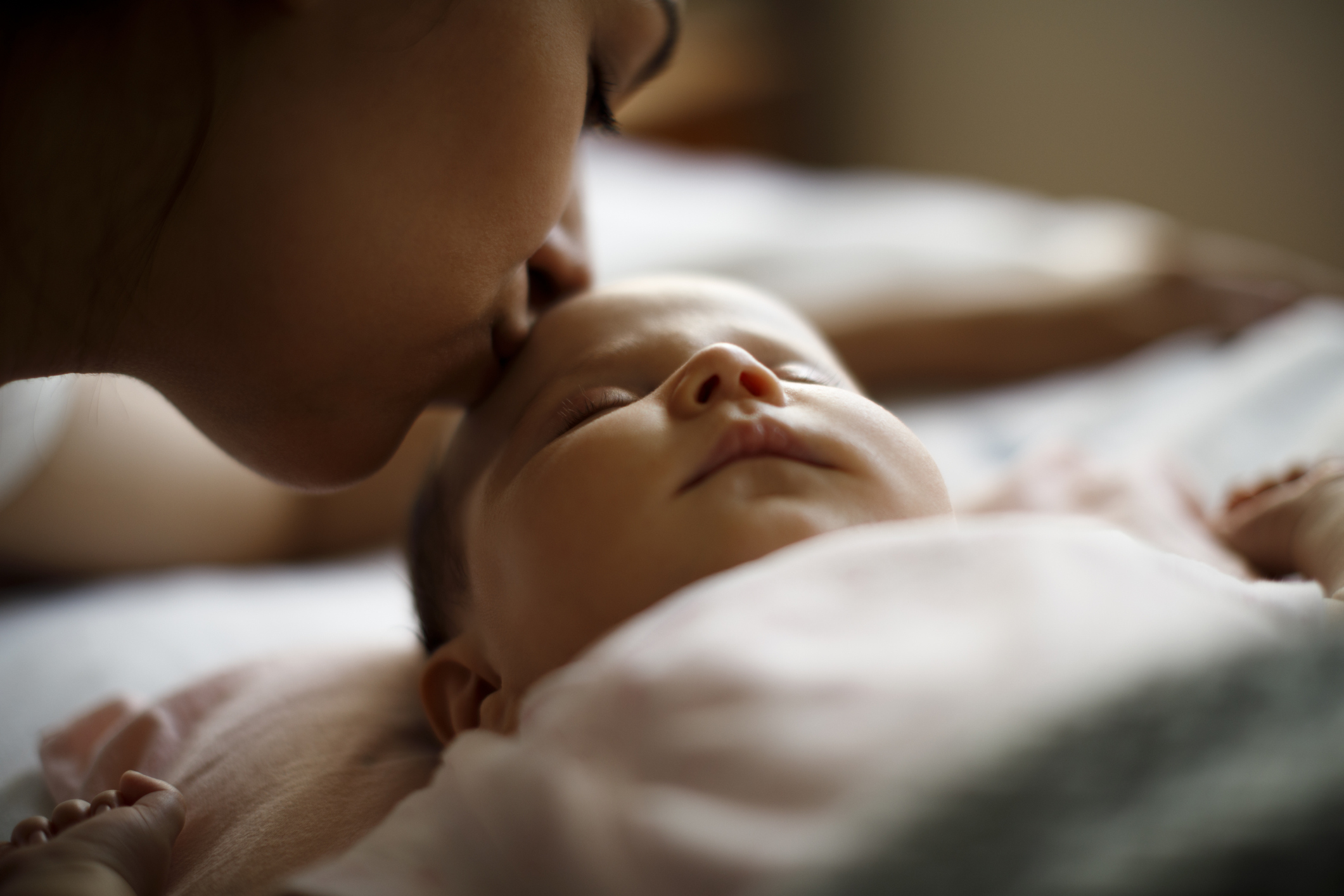 Mother kissing her sleeping newborn baby