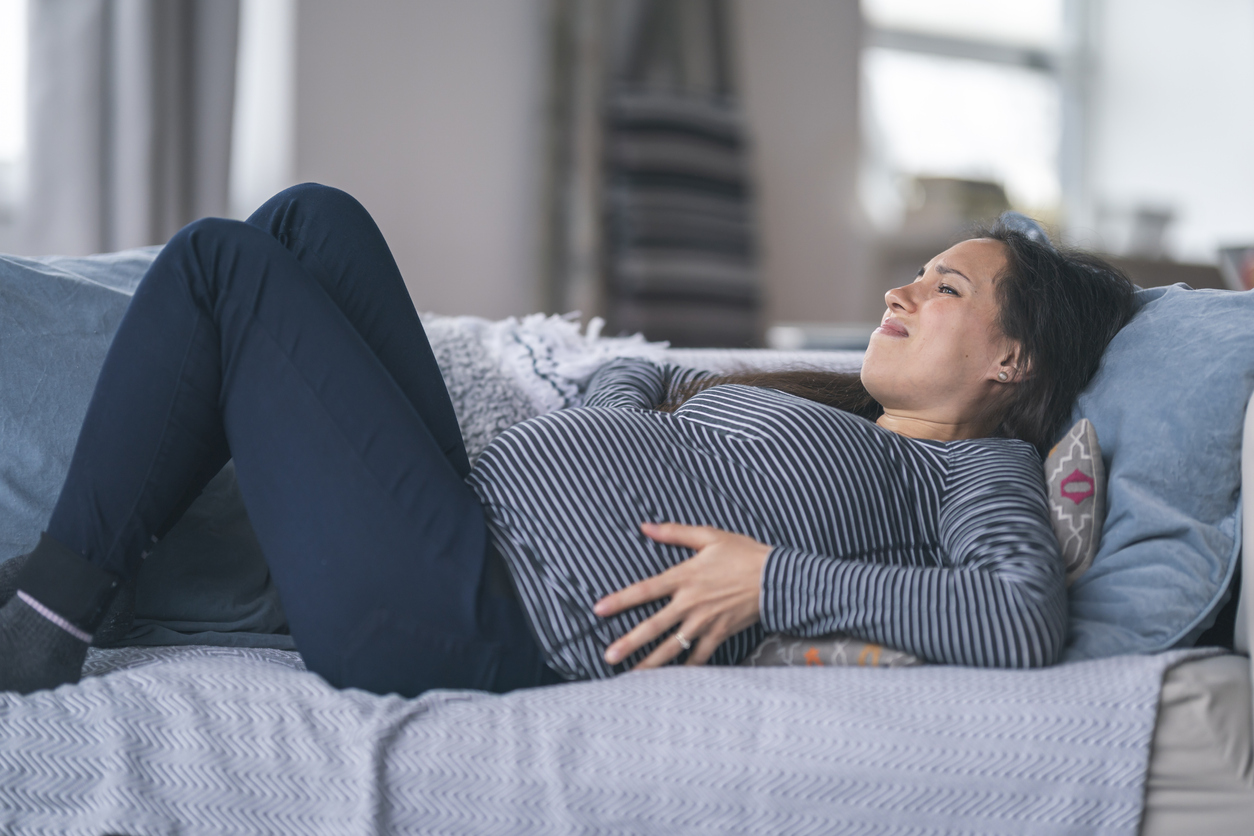 Pregnant woman with back pain resting on couch