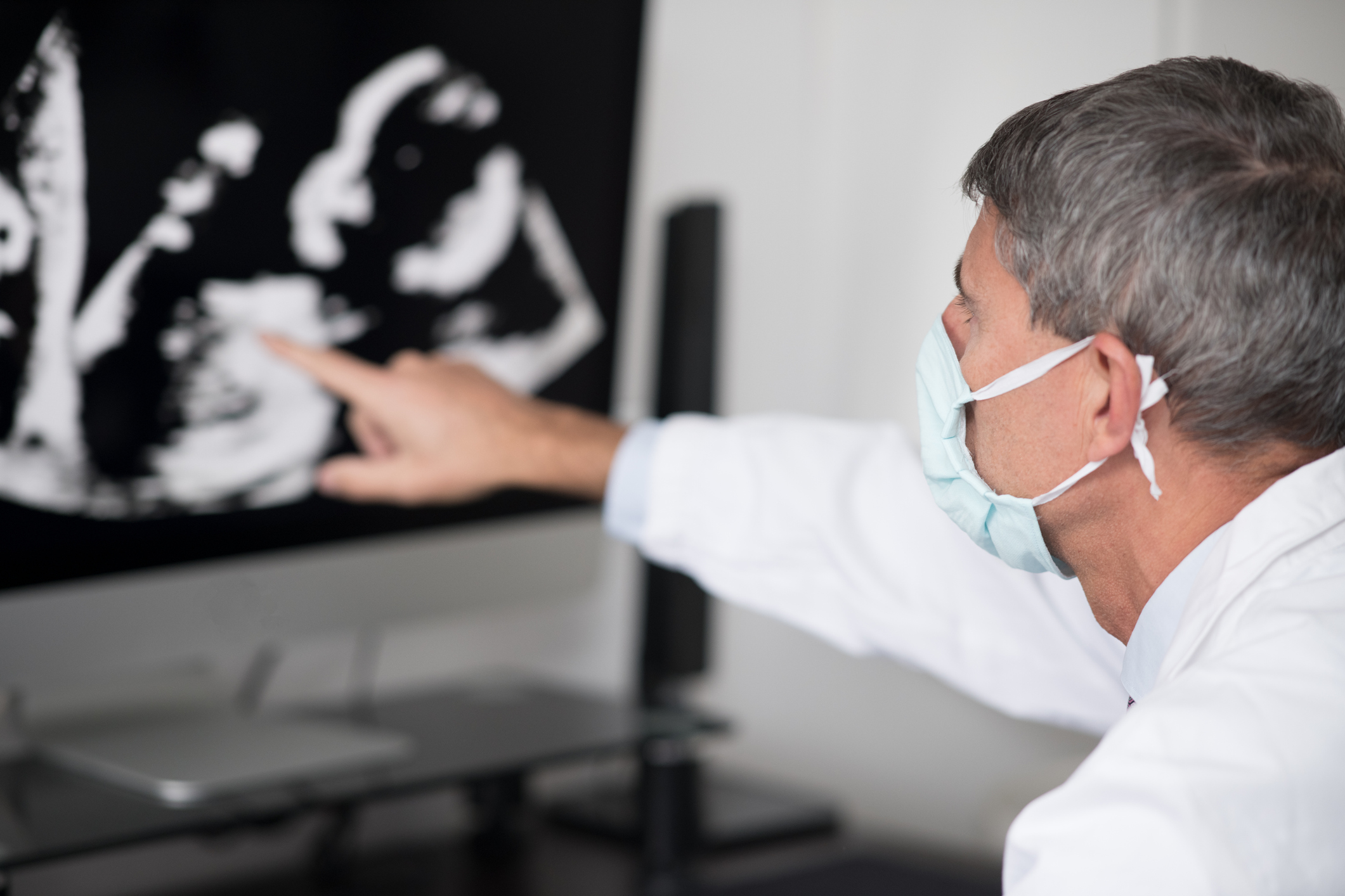 Covid-19. Hospital.  Portrait of doctor with surgical mask in hospital study while he is analyzing a fetal ultrasound