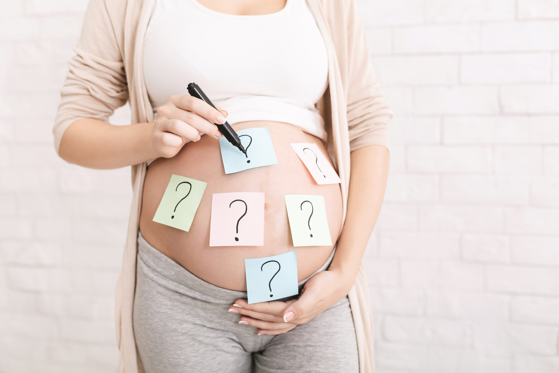 Pregnant woman embracing her belly with question mark on it