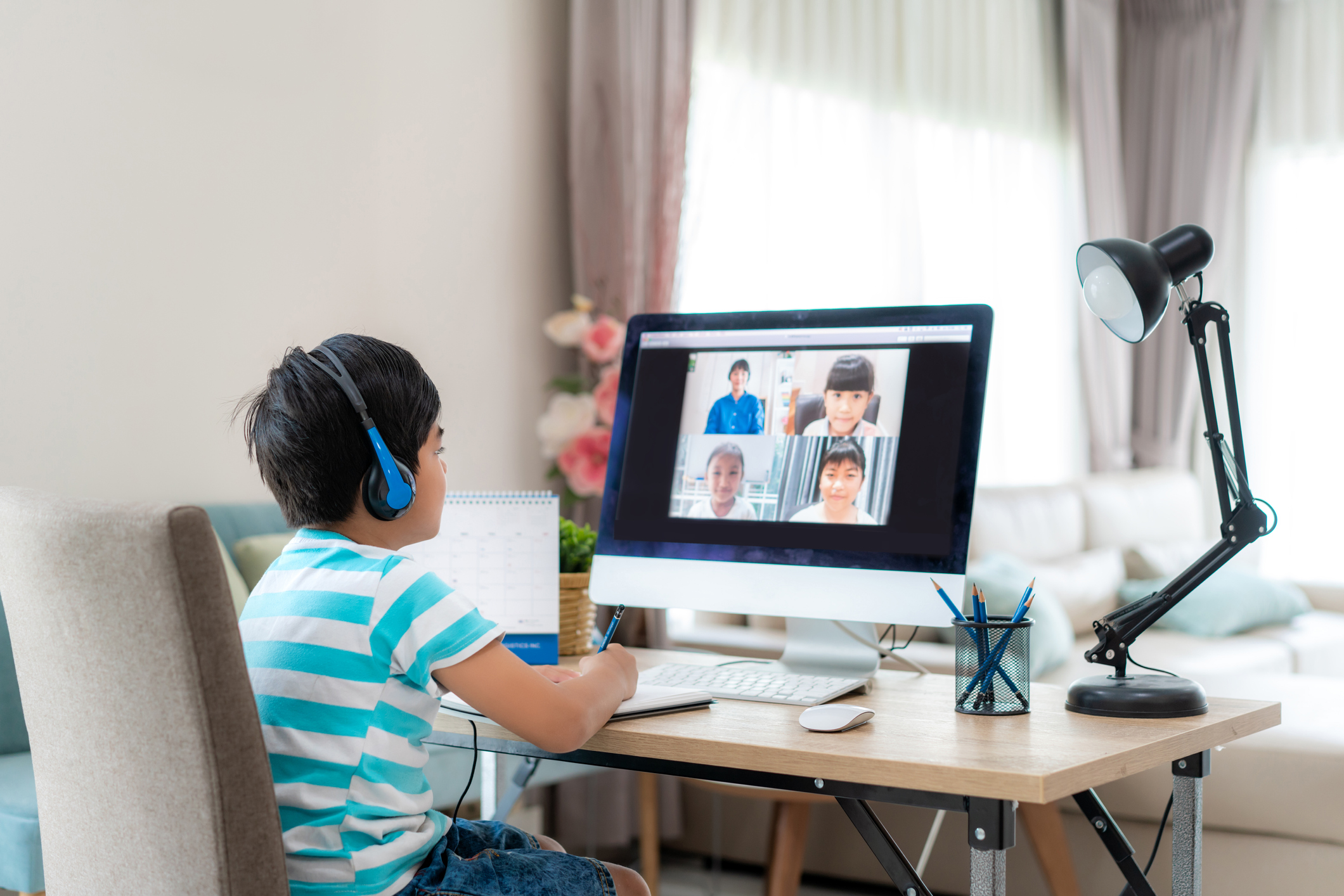 Asian boy student video conference e-learning with teacher and classmates on computer in living room at home. Homeschooling and distance learning ,online ,education and internet.