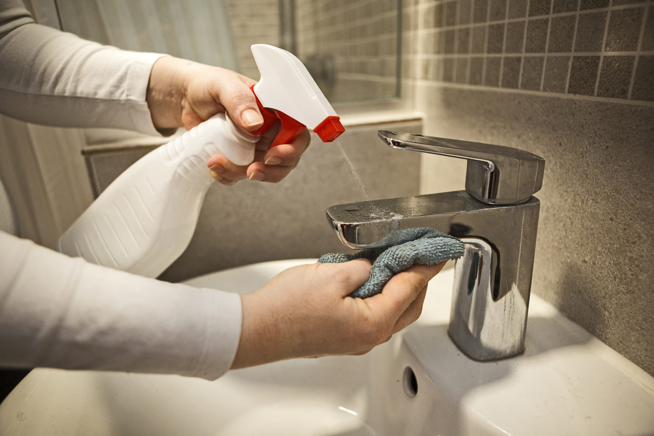 Young woman applies an alcohol-based antiseptic spray to a water tap