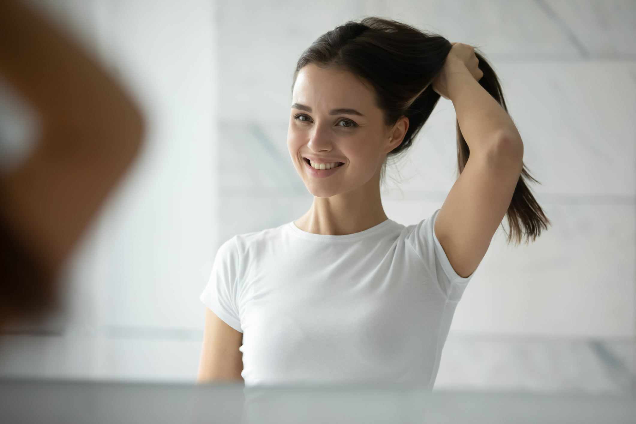 Young woman hold healthy thick hair looking in mirror