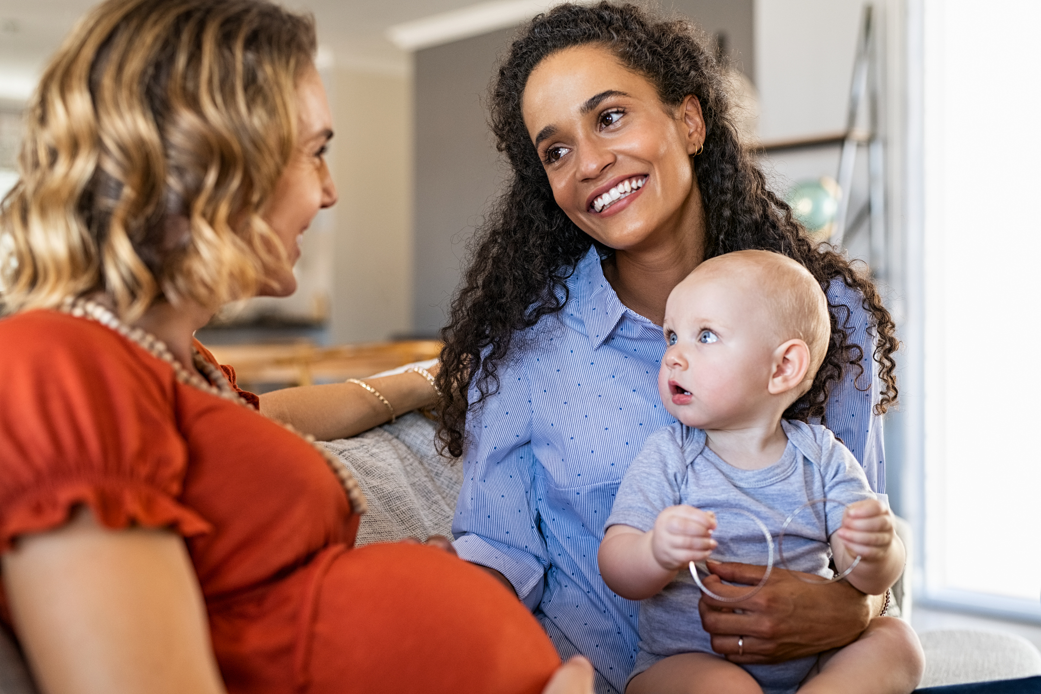 Multiethnic women friends talking and playing with child