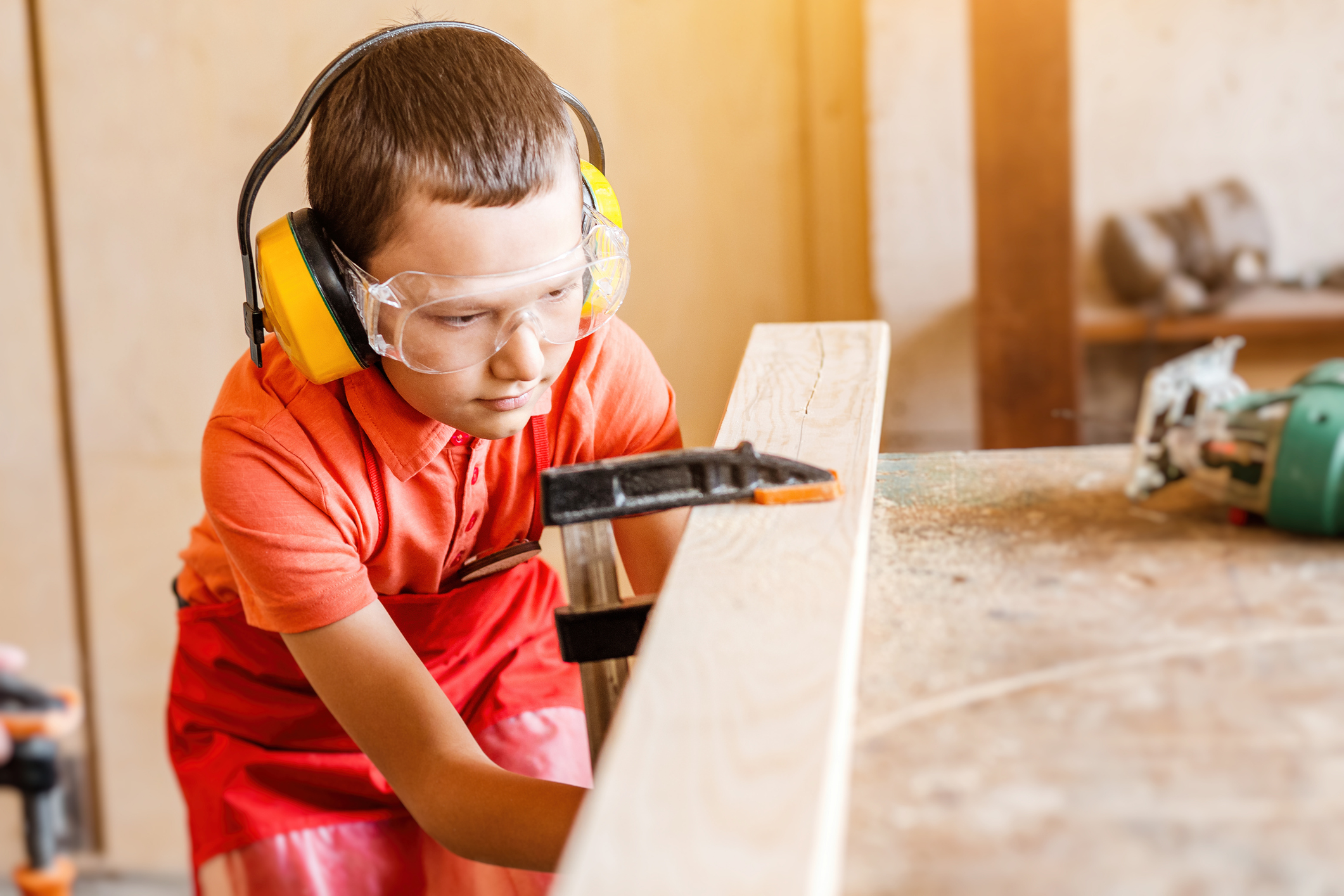 boy in the workshop independently learns to work with wood in the carpentry workshop. The concept of a useful hobby in childhood and learning to work manually with hands