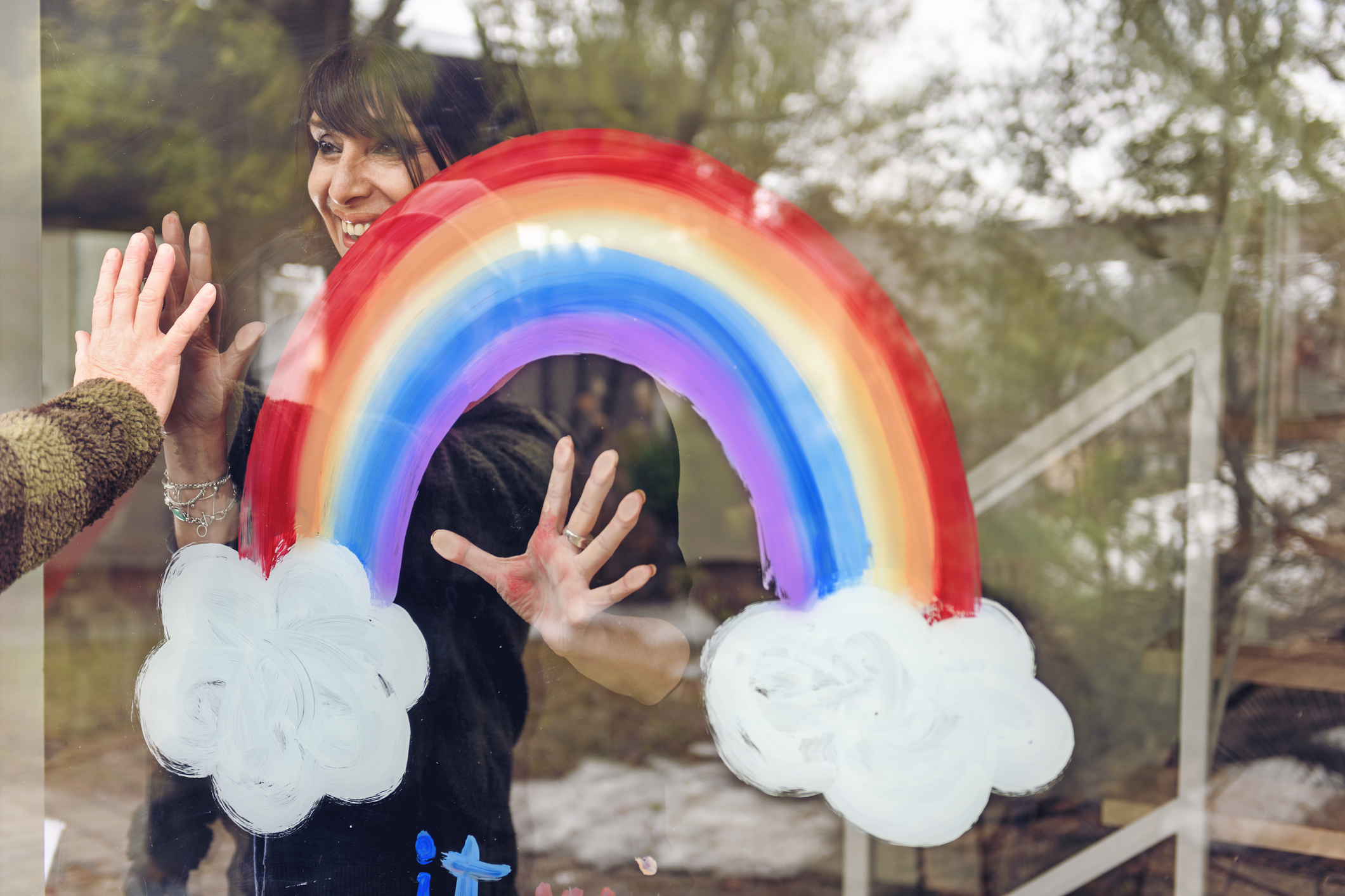 Woman painting a rainbow on a window