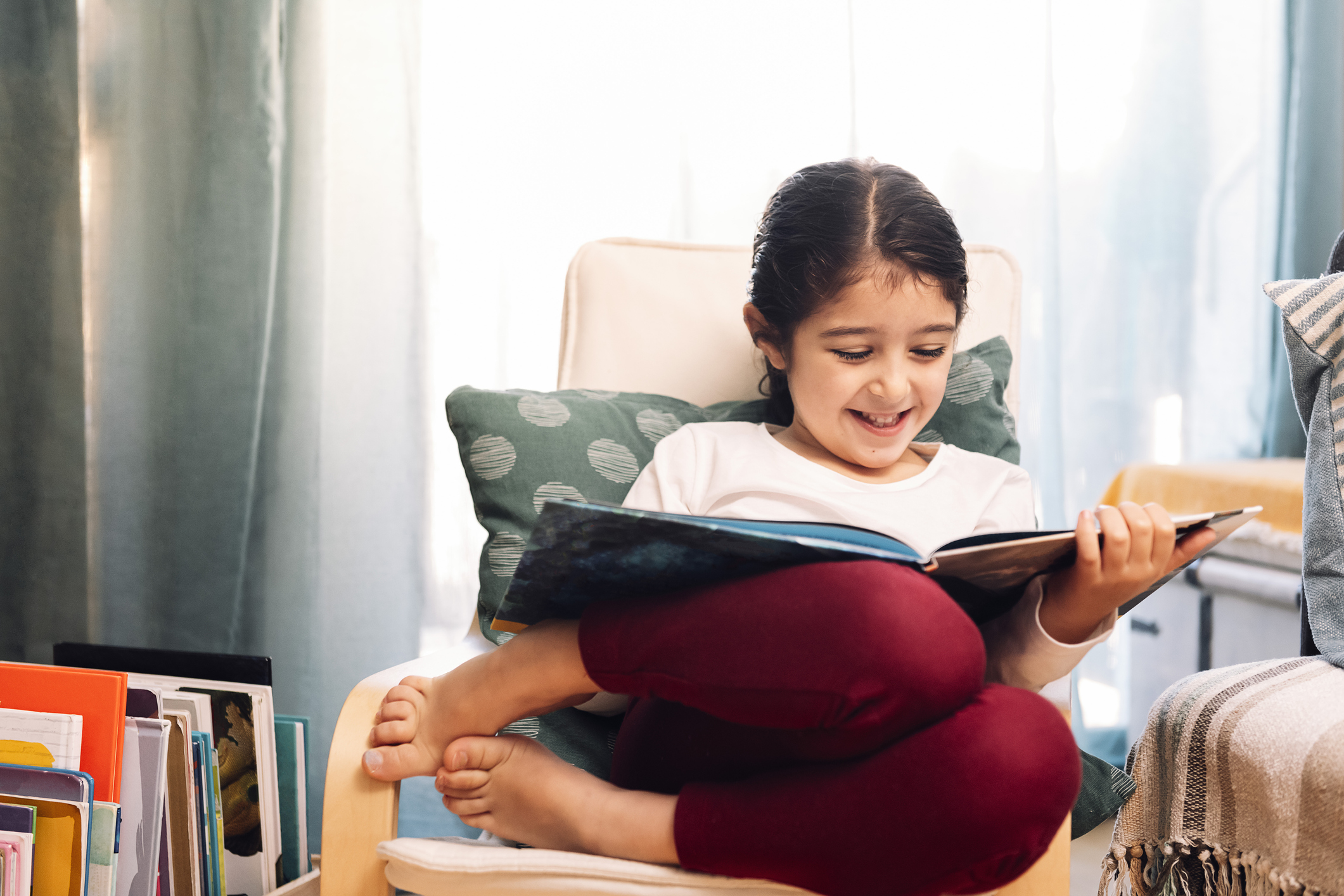 smiling girl reading sitting at home