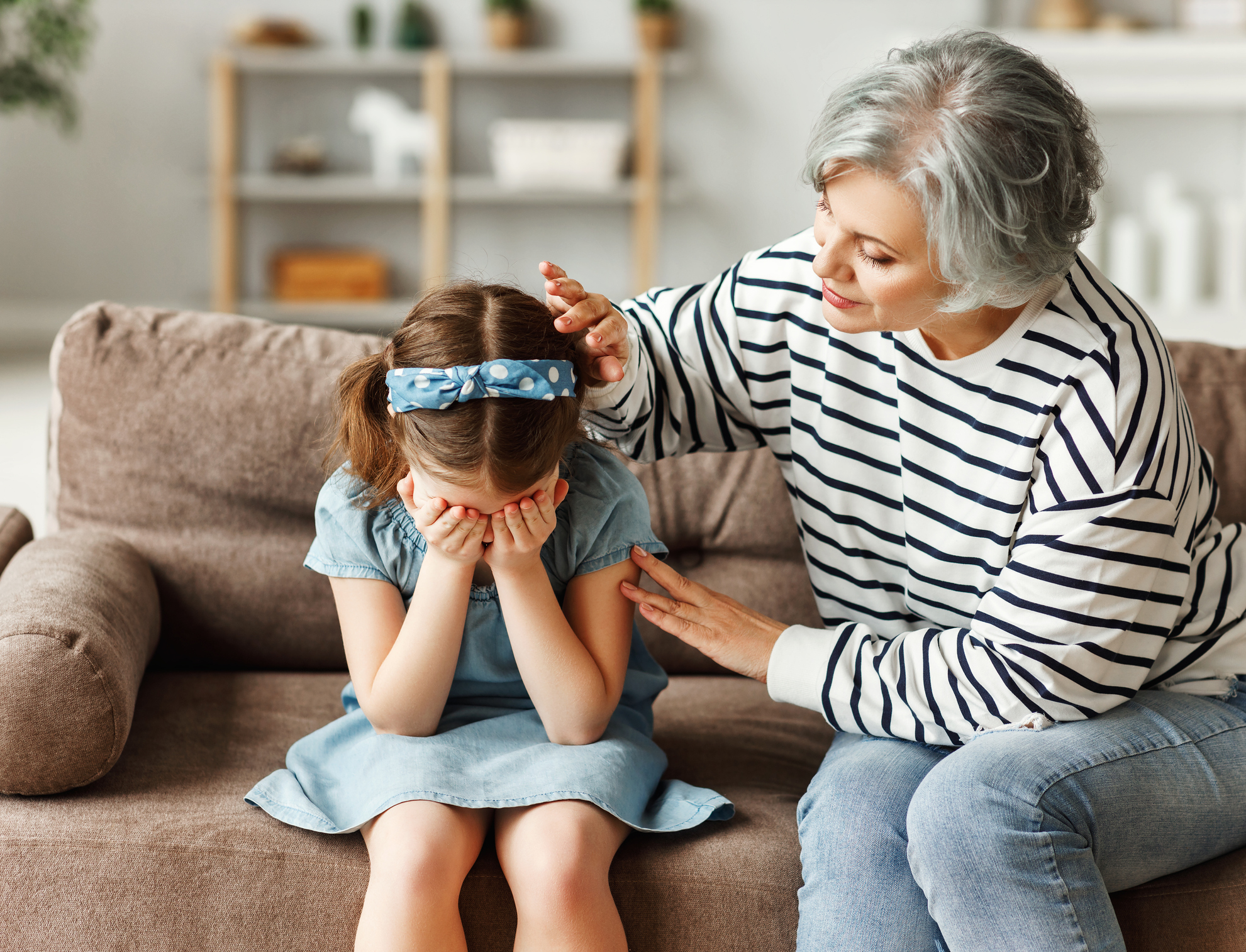 Grandmother supporting crying granddaughter at home