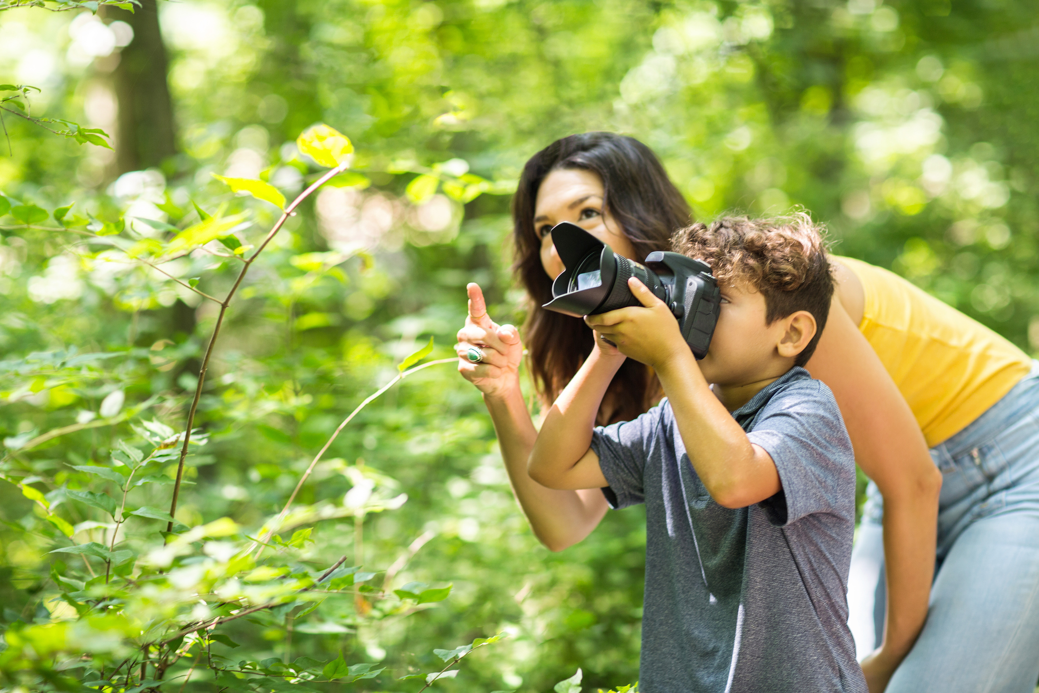 Little boy taking photo with her mother in the woods.