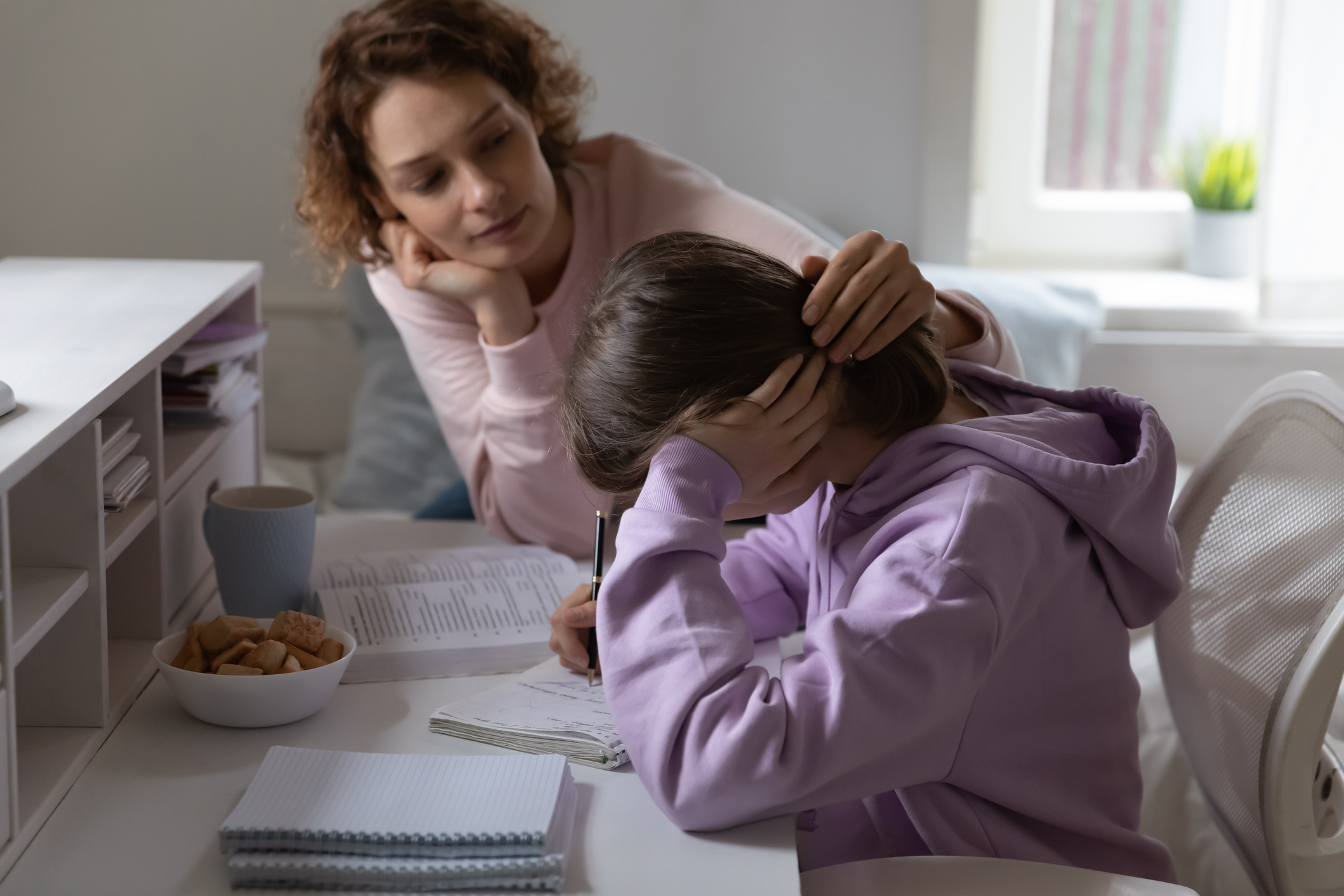 Loving mother supporting tired teenage daughter having difficulty with education