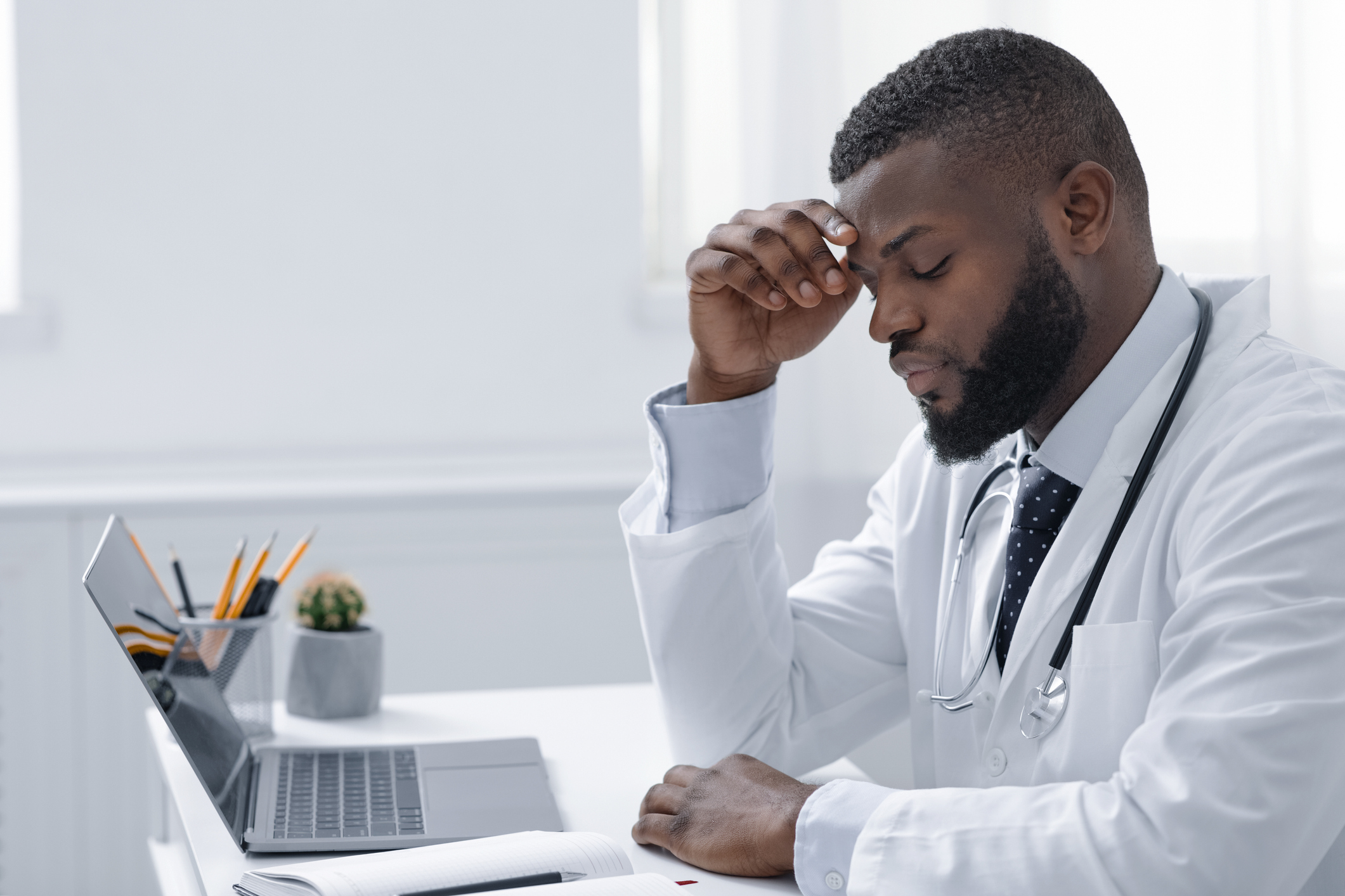 Overworked therapist sitting in clinic in front of laptop