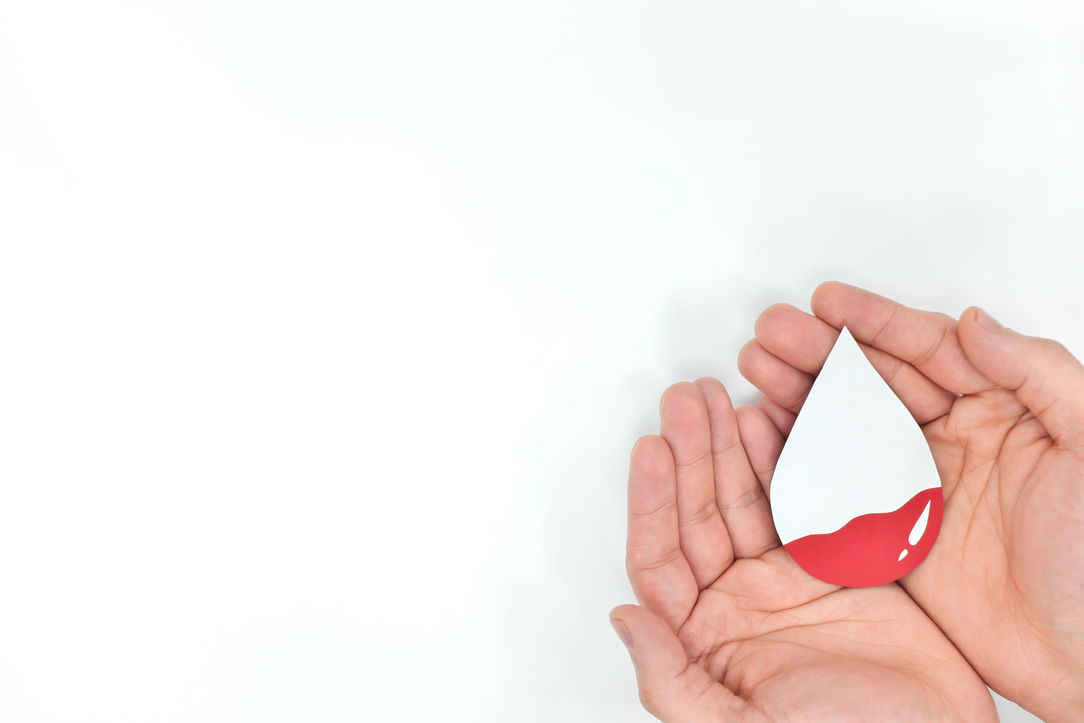 Blood transfusion and World Blood Donor day concept. Hands holding blood drop. White background.