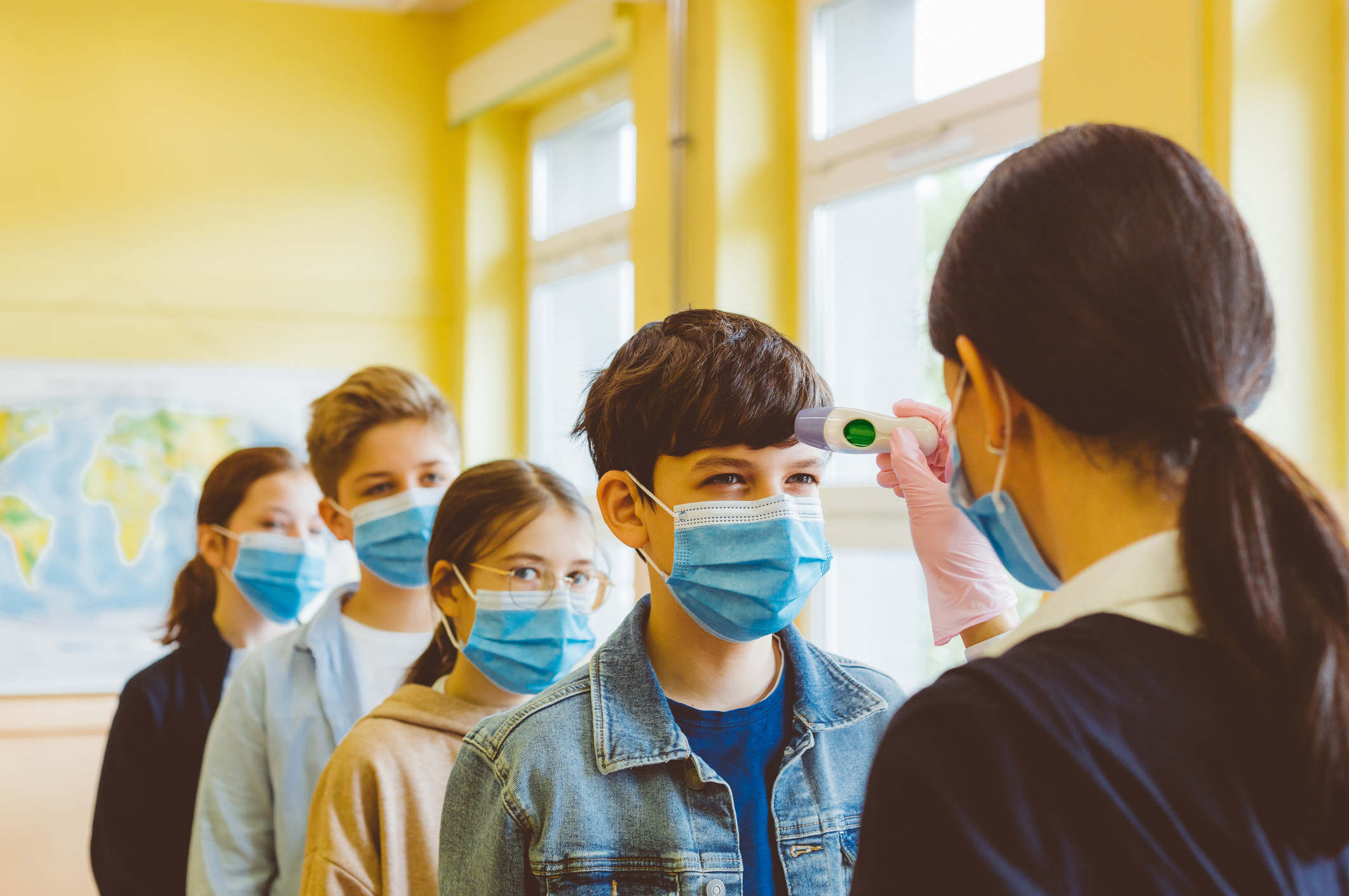 A teacher checks temperature of students at a high school