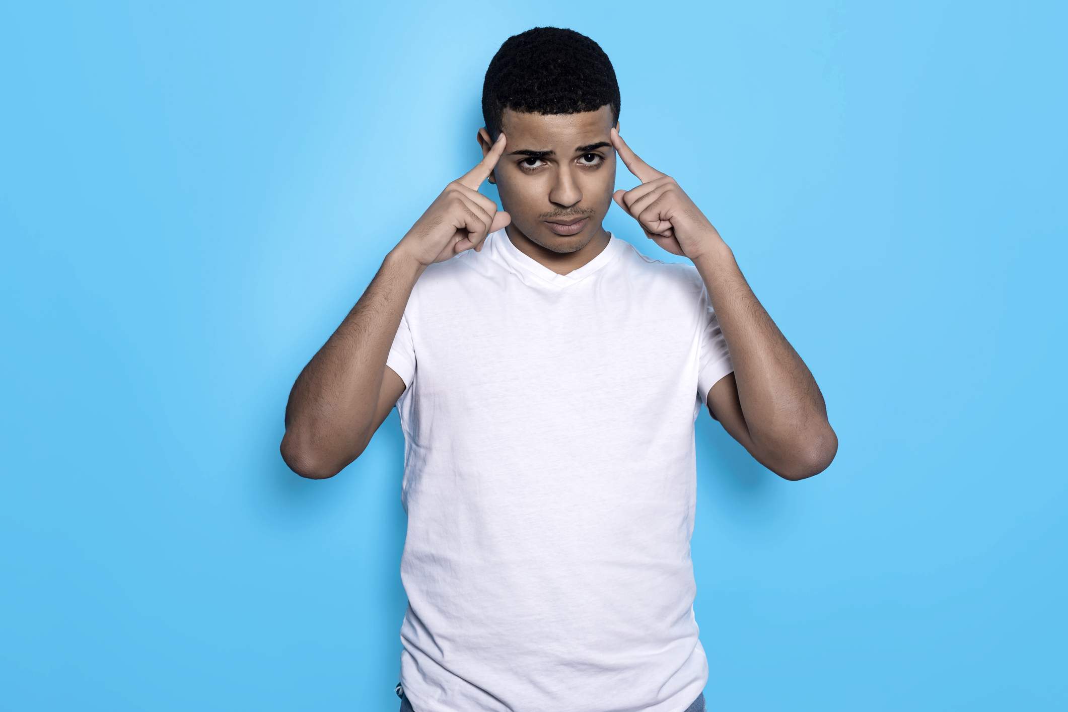 Horizontal portrait of black man in white t-shirt with fingers on temples, isolated on blue background