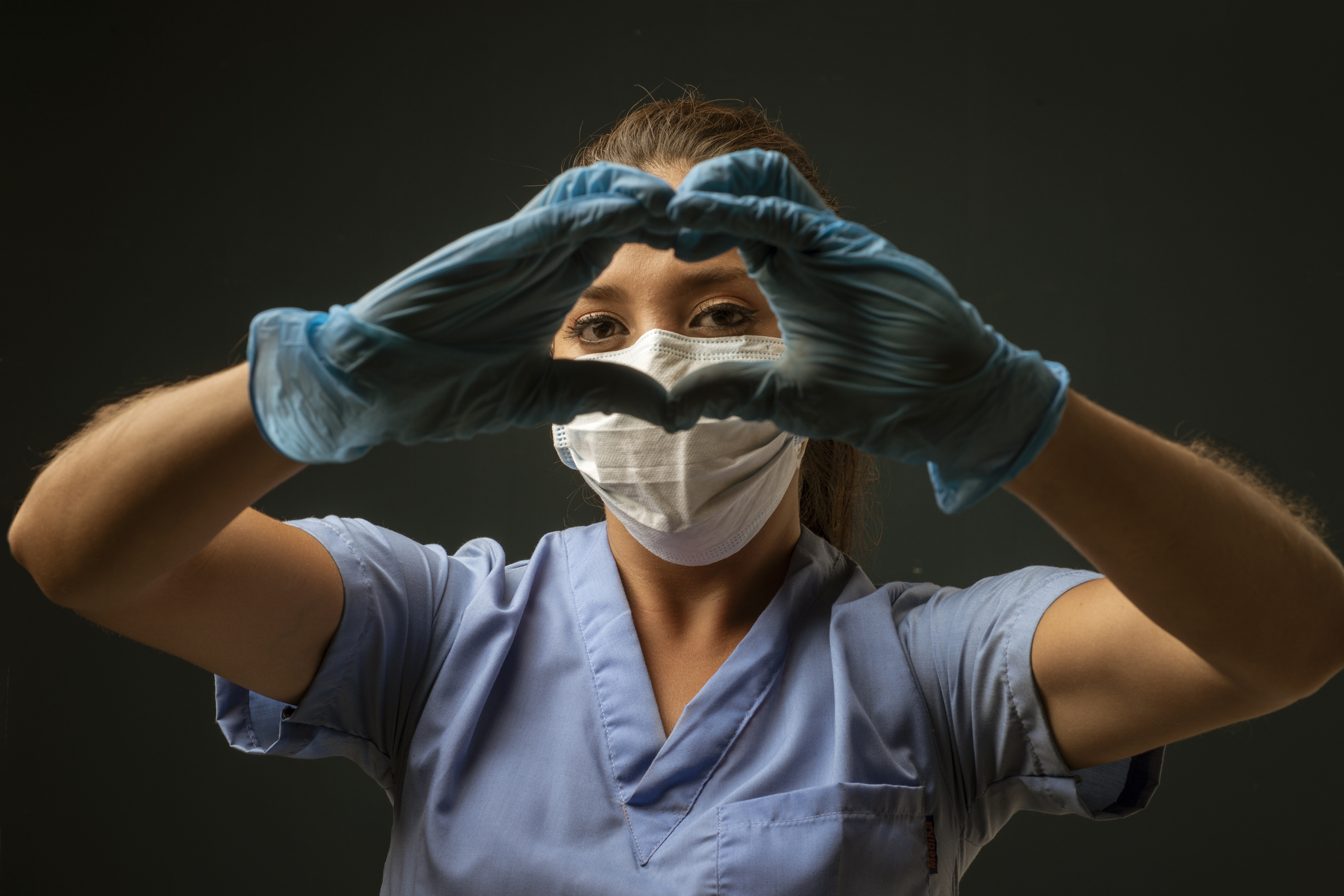 Nurse with gloves and mask thanking ereyone and making hearts