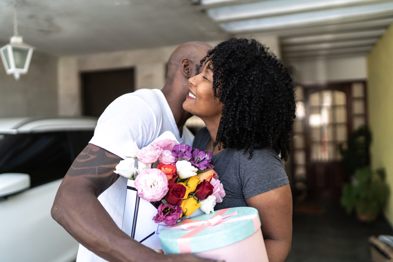 Husband surprising his wife with a flowers and present at home