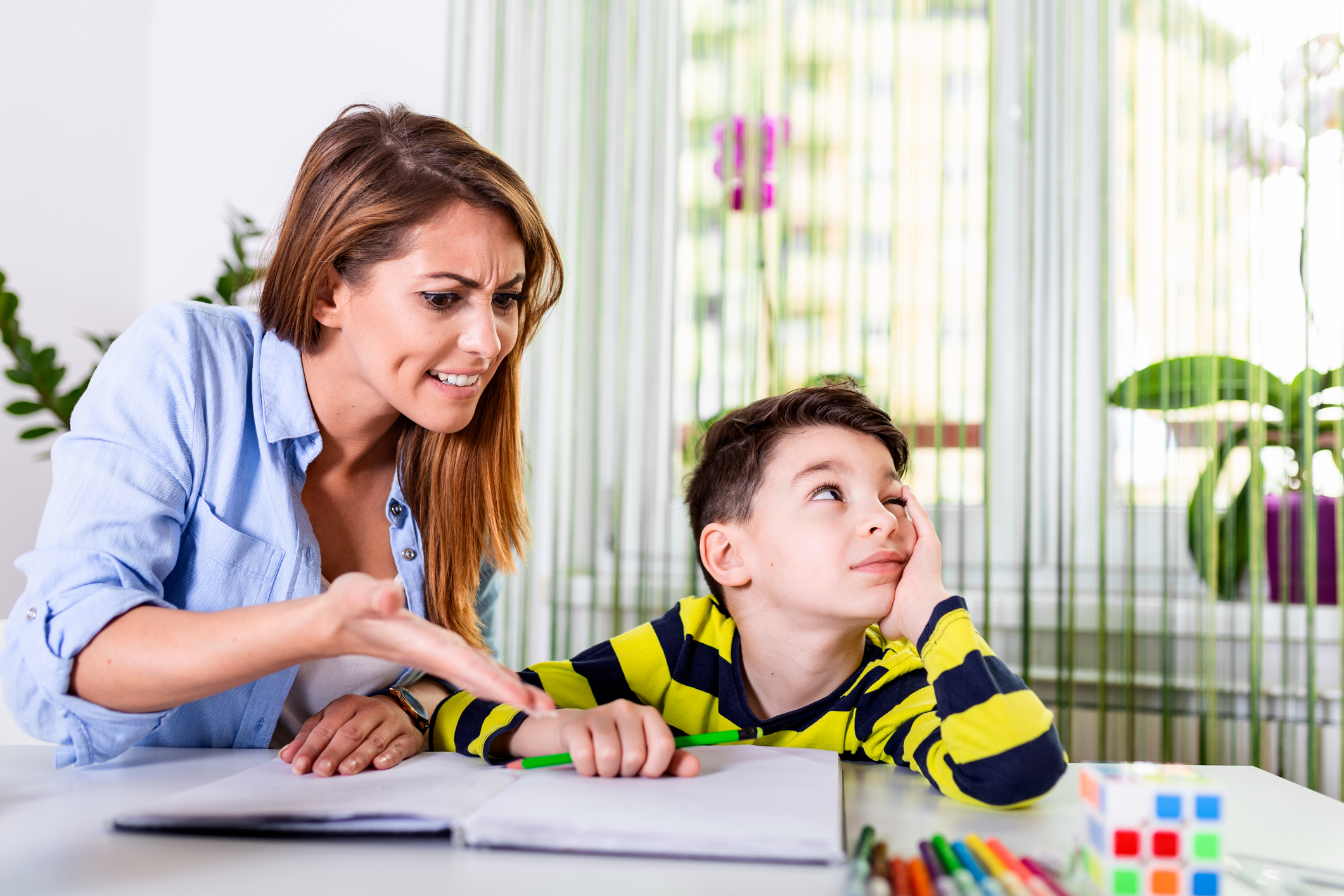 Do not ignore me when I am talking. Moms helping with homework. Mom is angry because her son dont want to do homework. Stressed mother and son frustrated over failure homework.