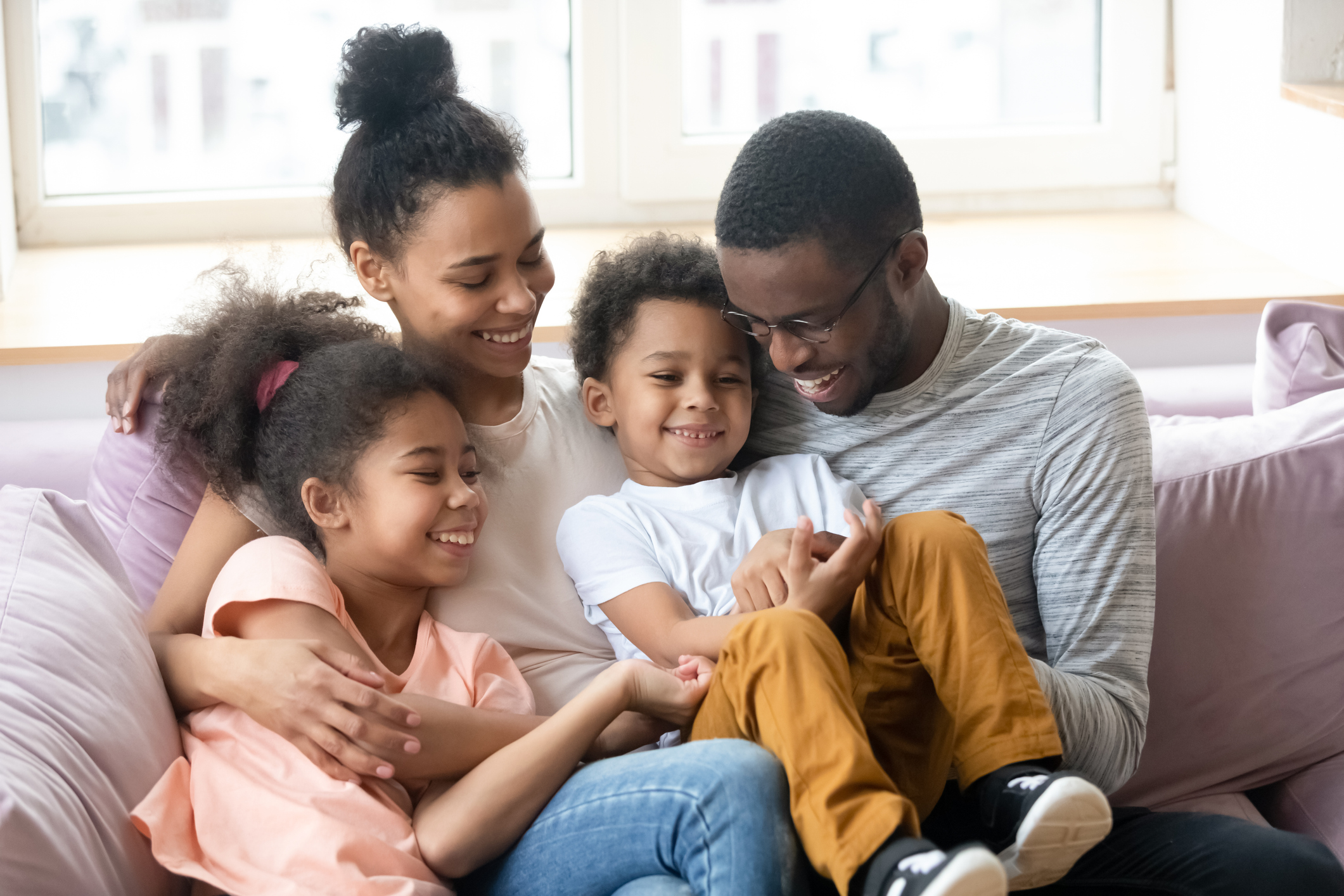 African parents with kids having fun sitting on couch indoors