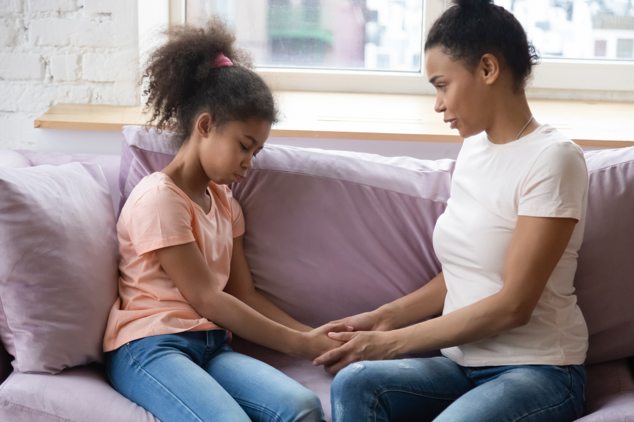 African mother and daughter hold hands having confidential conversation