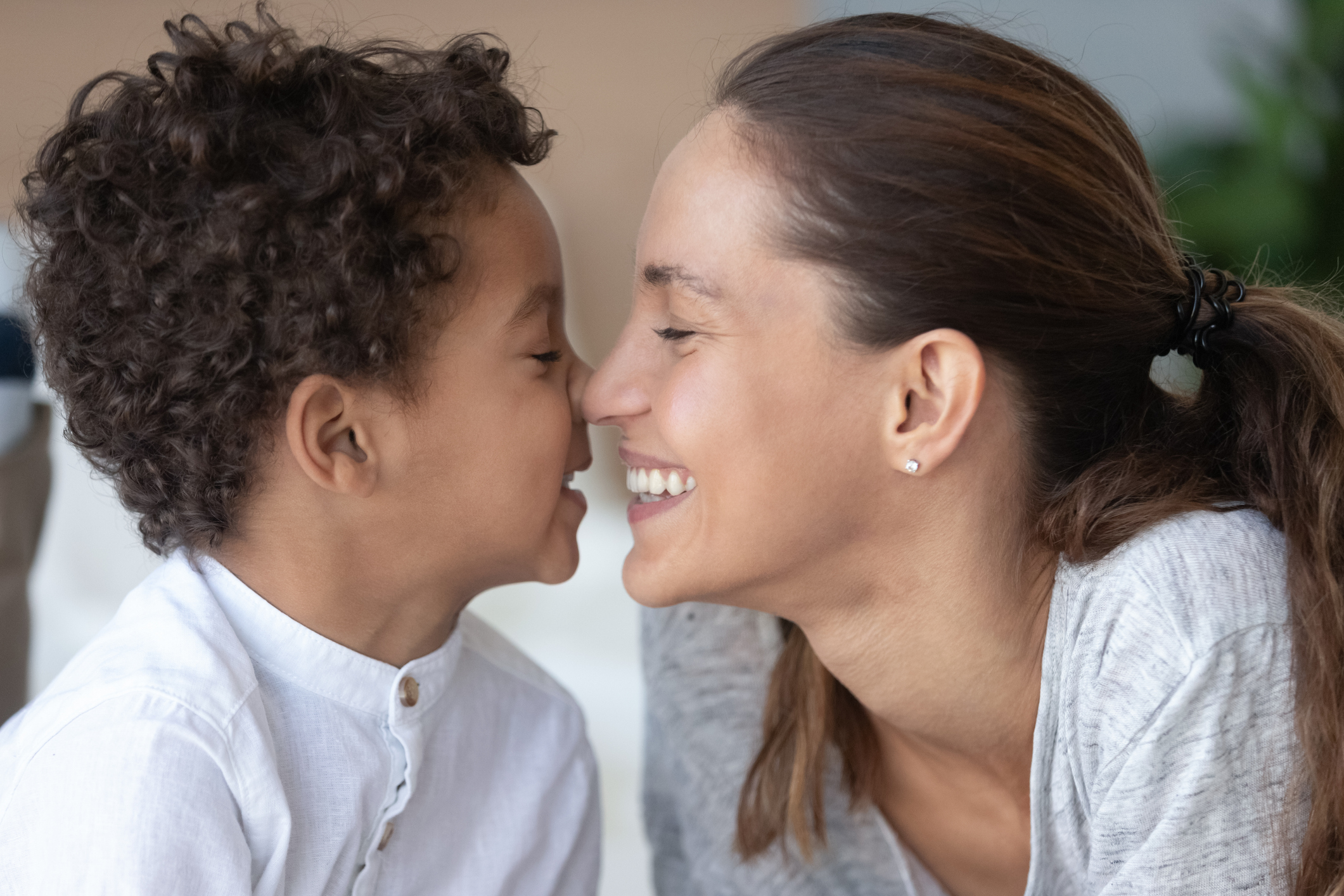 Loving mother and African American son touching noses close up