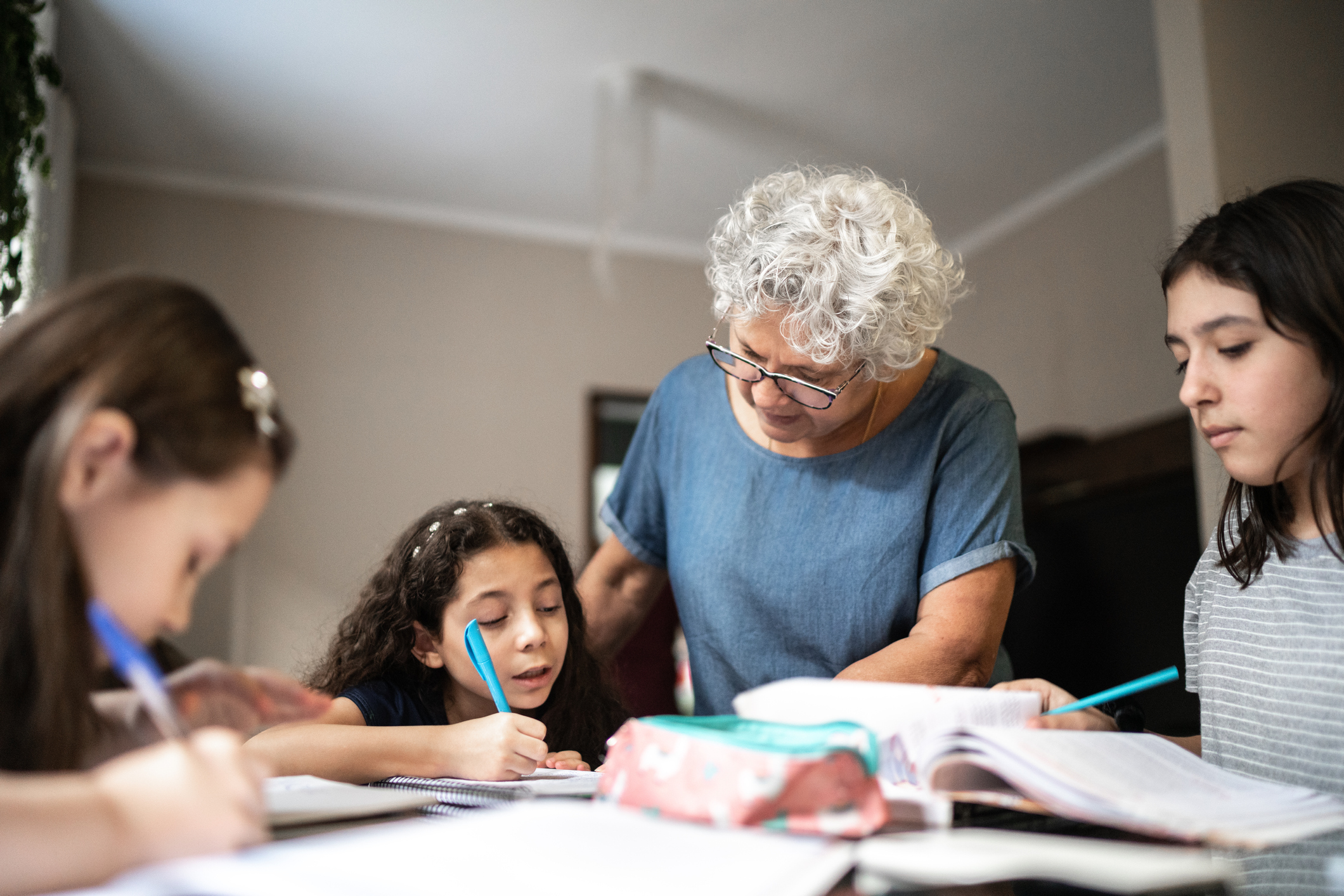 Grandmother helping granddaughter with homework while they studying at home