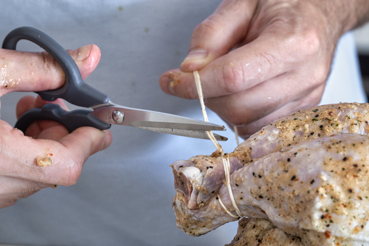 Man sews up a whole stuffed chicken. Preparing of festive dish with poultry. binding chicken. prepare food. cooking at home