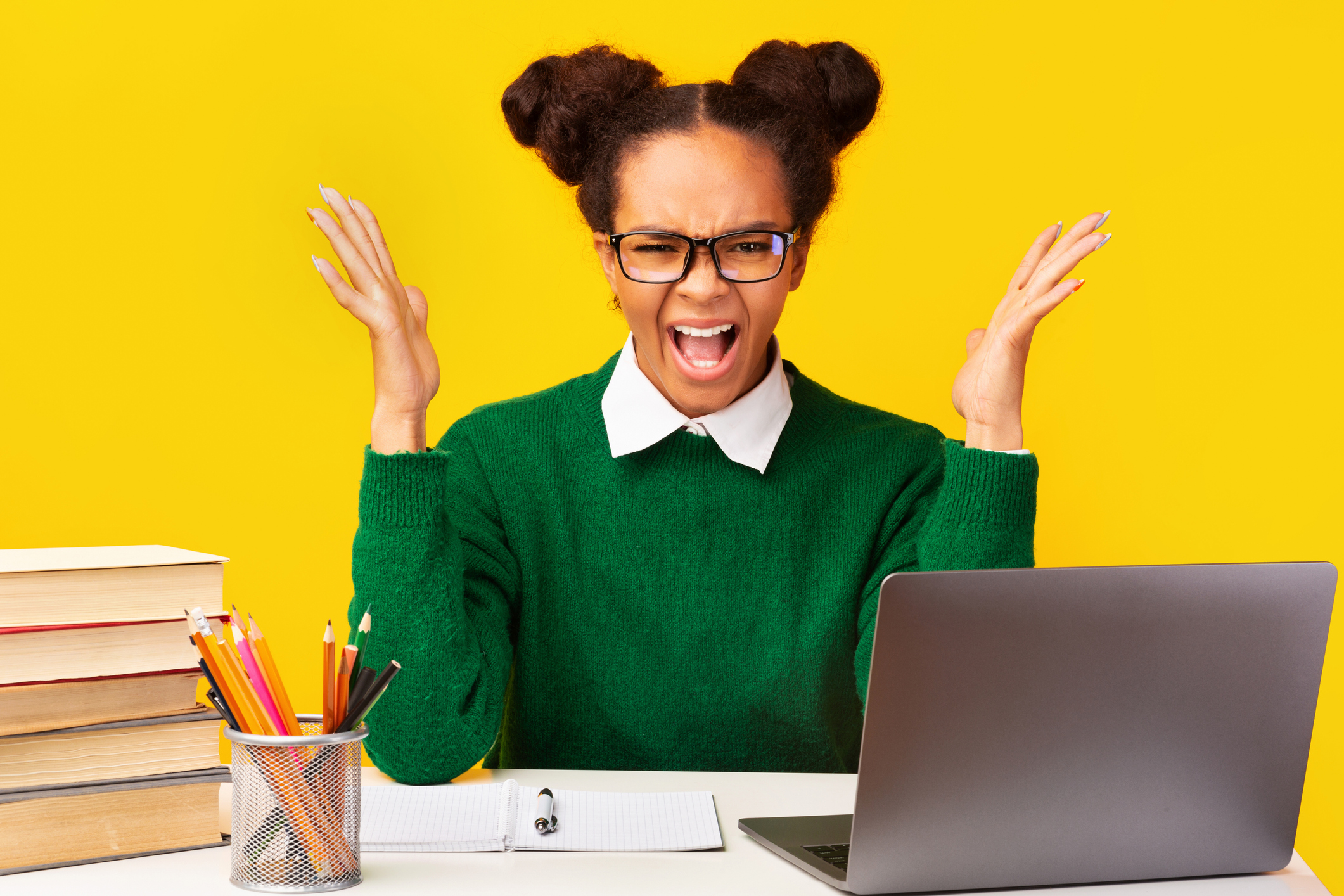 Nervous afro teen shouting sitting at desk