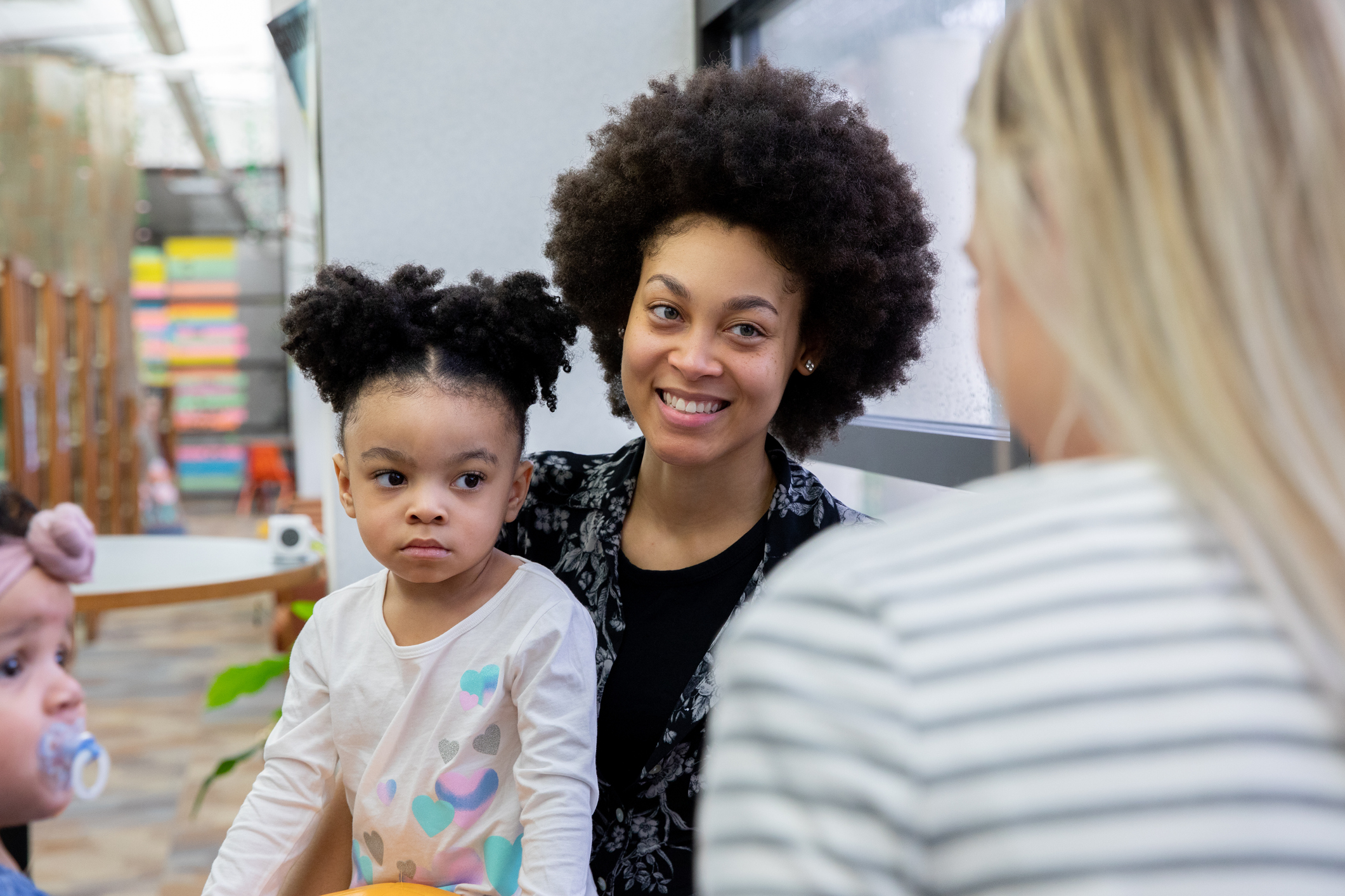 Beautiful young mother and her toddler daughter meet with friends during support or play therapy group