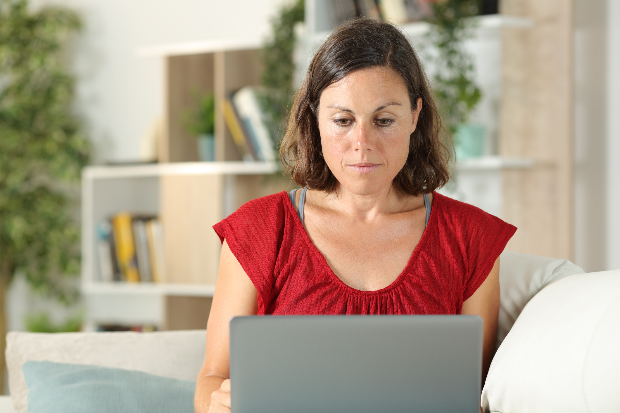 Serious adult woman using laptop sitting at home