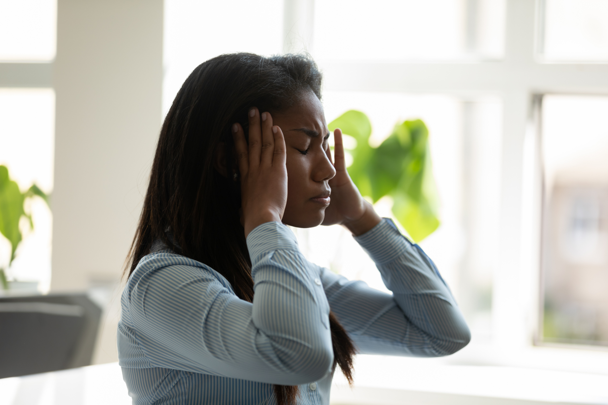 Unhappy african american businesswoman suffering from headache at work.