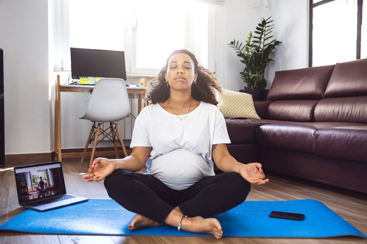 Pregnant woman practicing Yoga with online video class