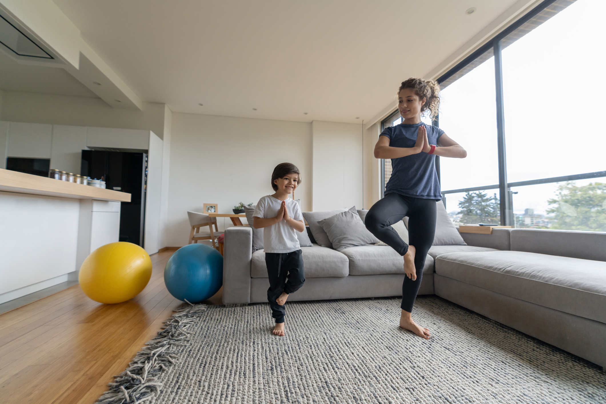 Mother teaching yoga to her son at home