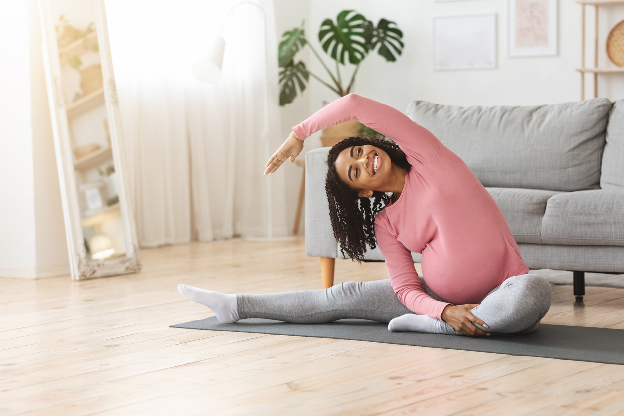 Positive african pregnant woman doing morning exercise at home