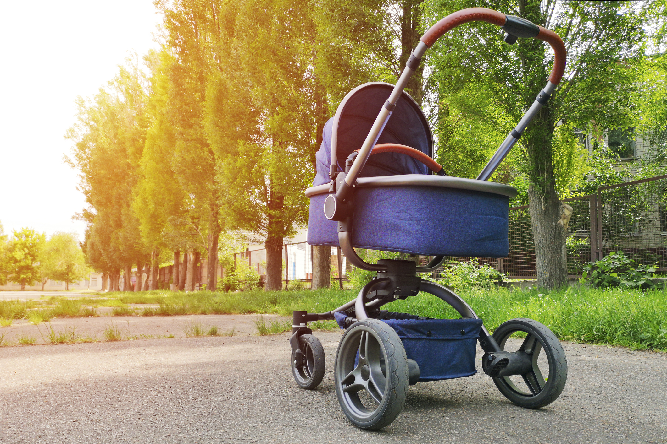 One pram baby in the park on a sunny day. Parent walking with carriage in city park