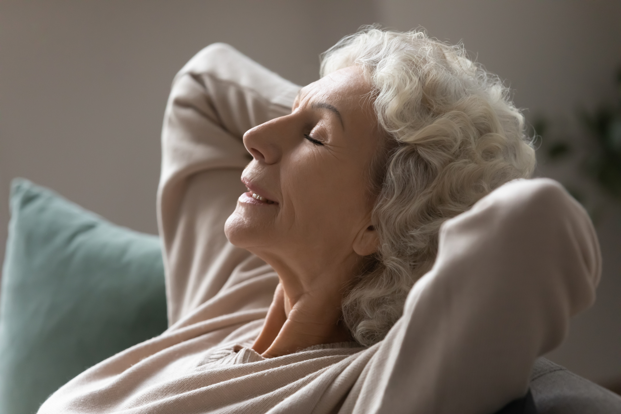 Grandmother put hands behind head relaxing on couch closeup photo