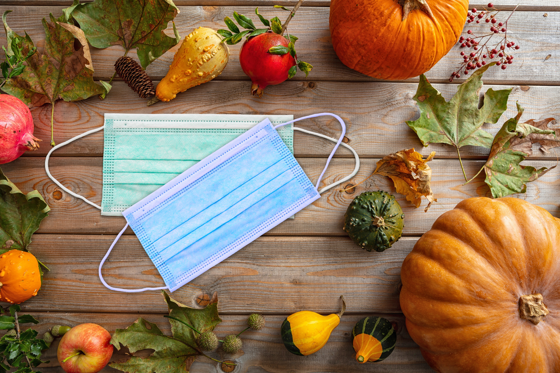 Protective mask and thanksgiving pumpkins against wooden background