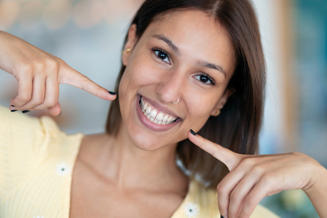 Beautiful young woman with perfect white smile looking at camera at home.