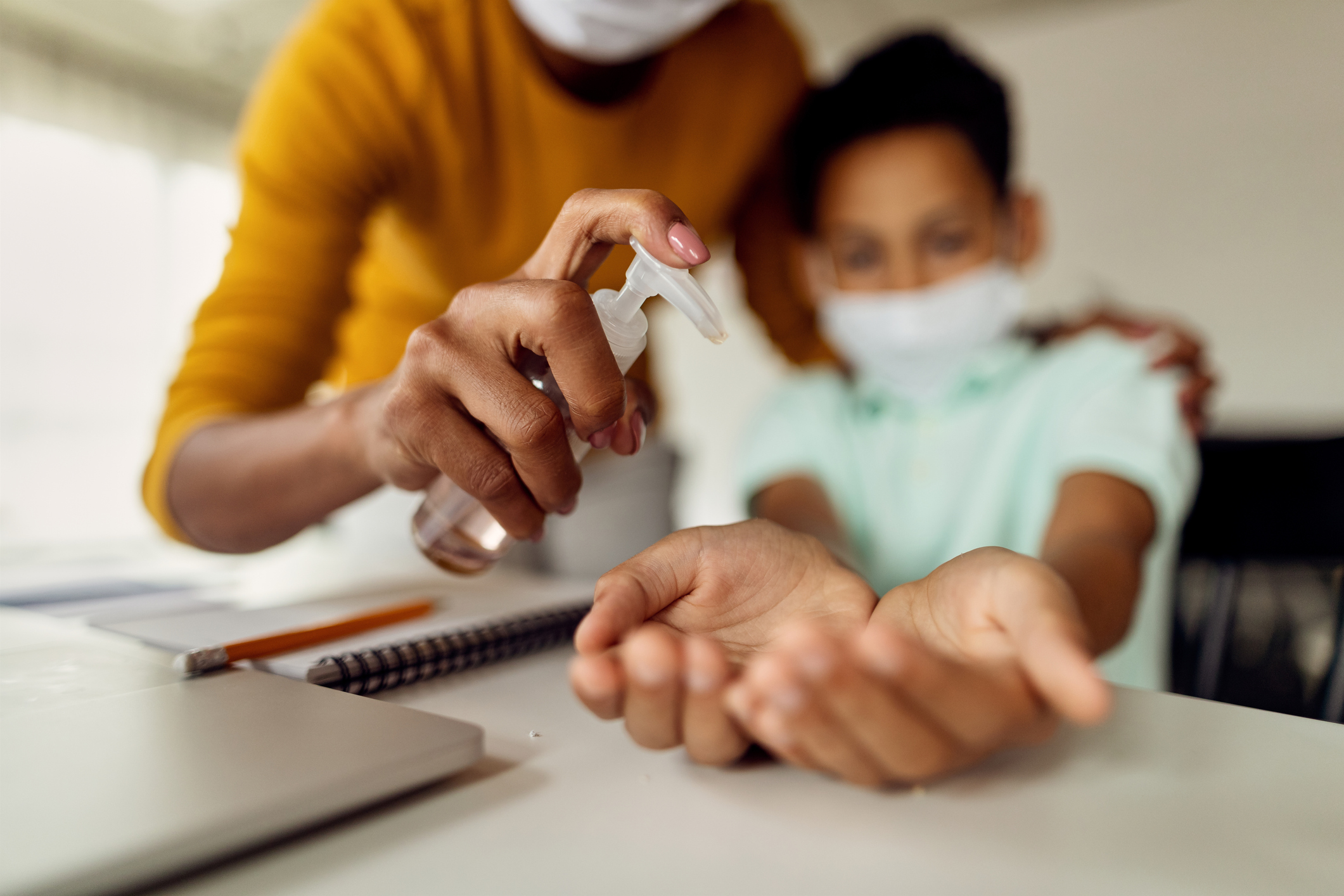 Close-up of mother disinfecting son's hands due to virus pandemic.