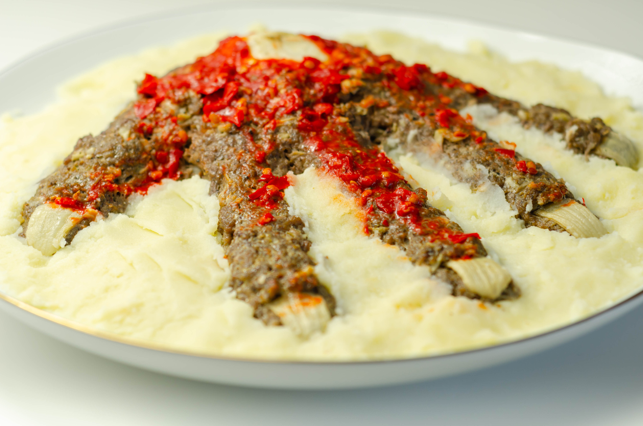 Roasted minced meat formed in the shape of a hand, topped with a tomato and pepper sauce, a creative way of serving food for Halloween