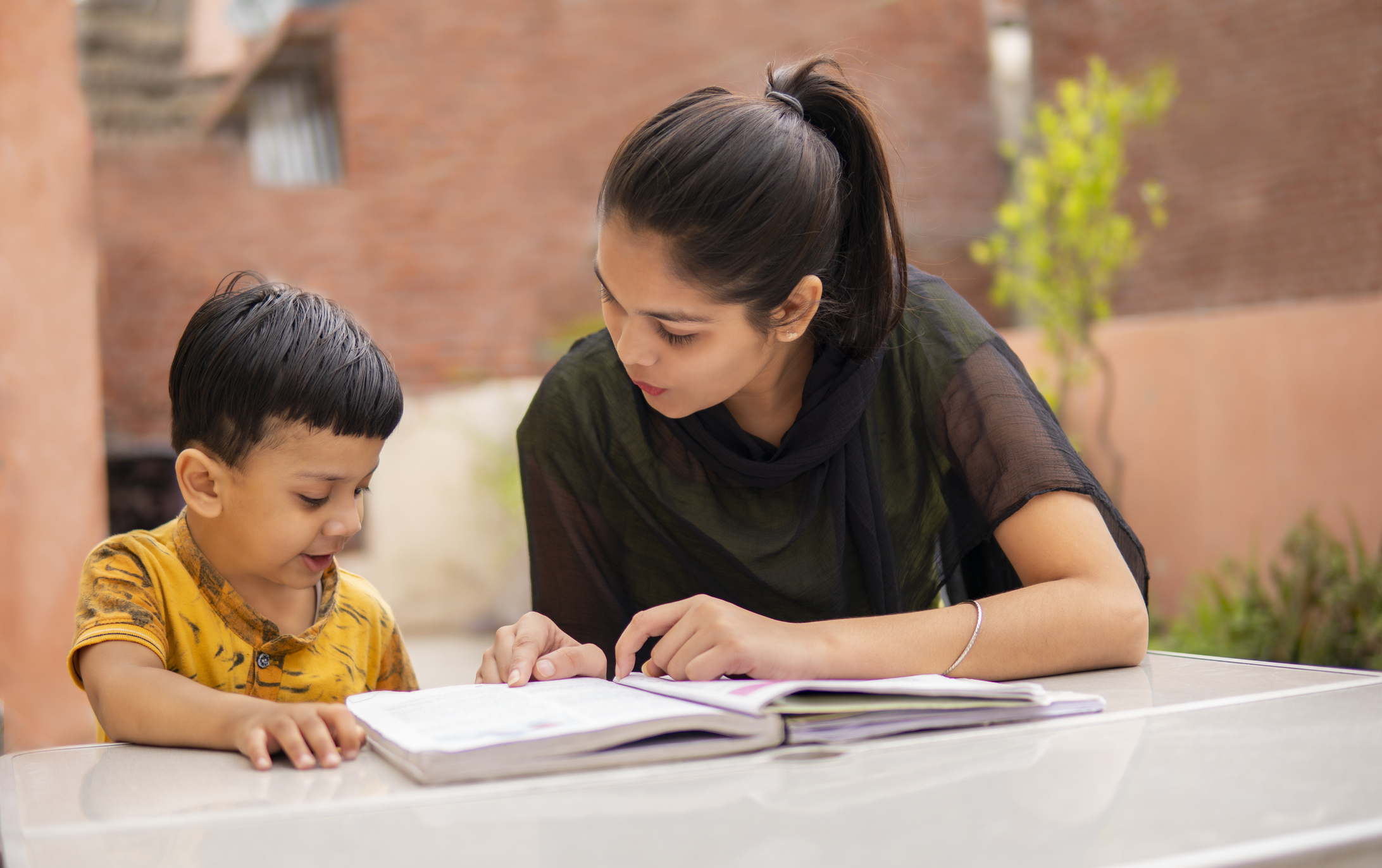 Indian young girl tutor teaching a little boy.