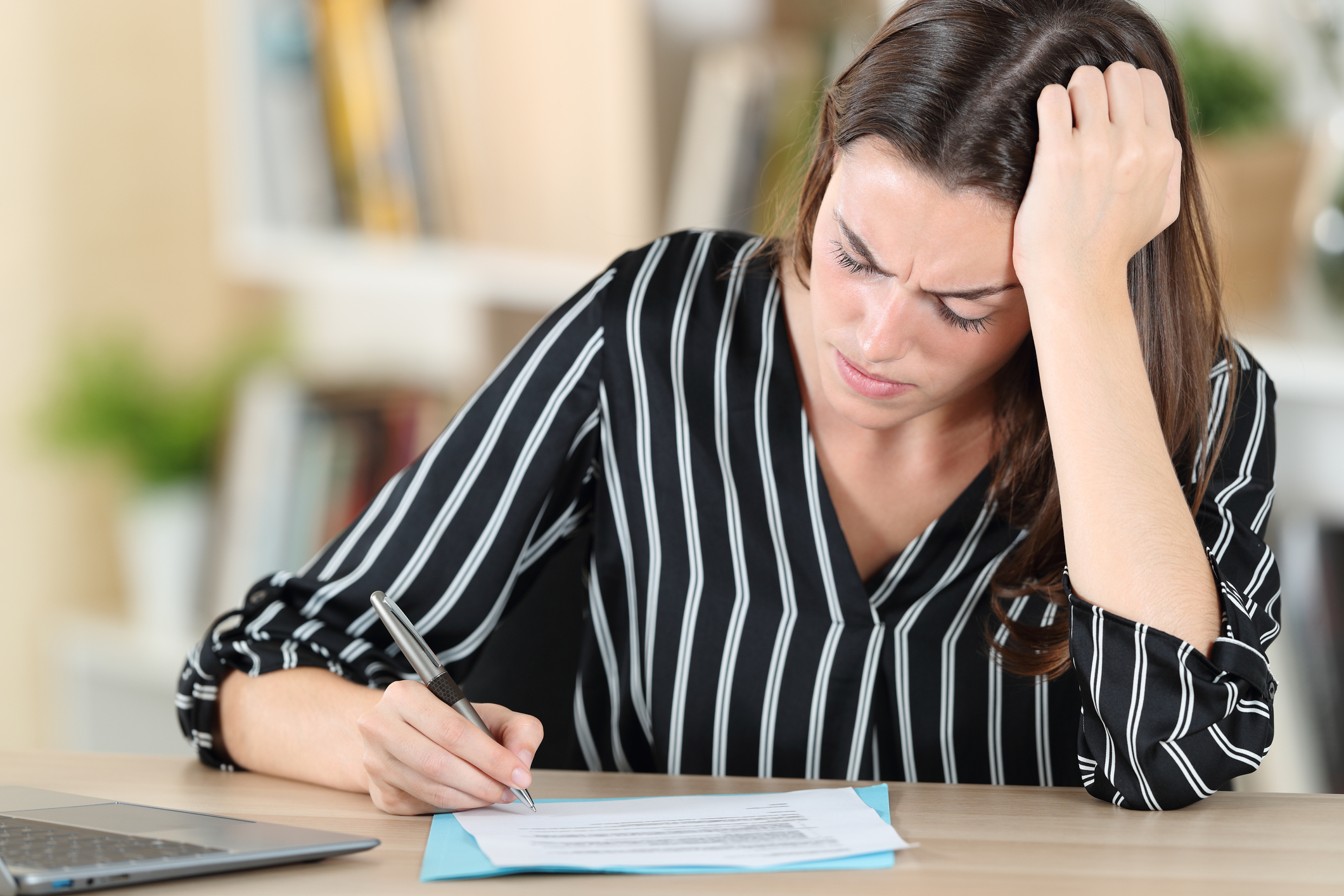 Worried woman signing document on a desk at home