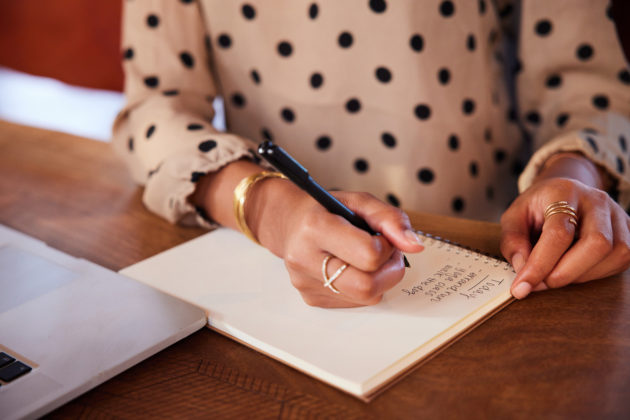 Businesswoman writing a to do list while working at a table