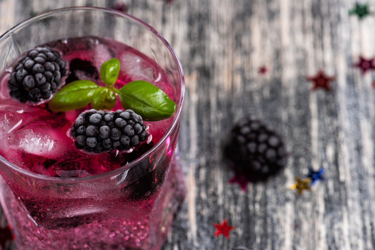 Sparkling alcoholic cocktail with a blackberry and basil