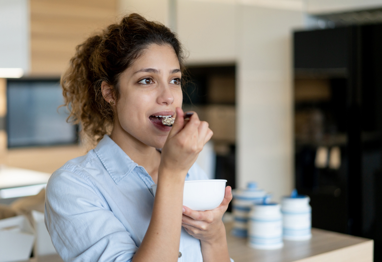 Woman at home eating a bowl of cereals for breakfast