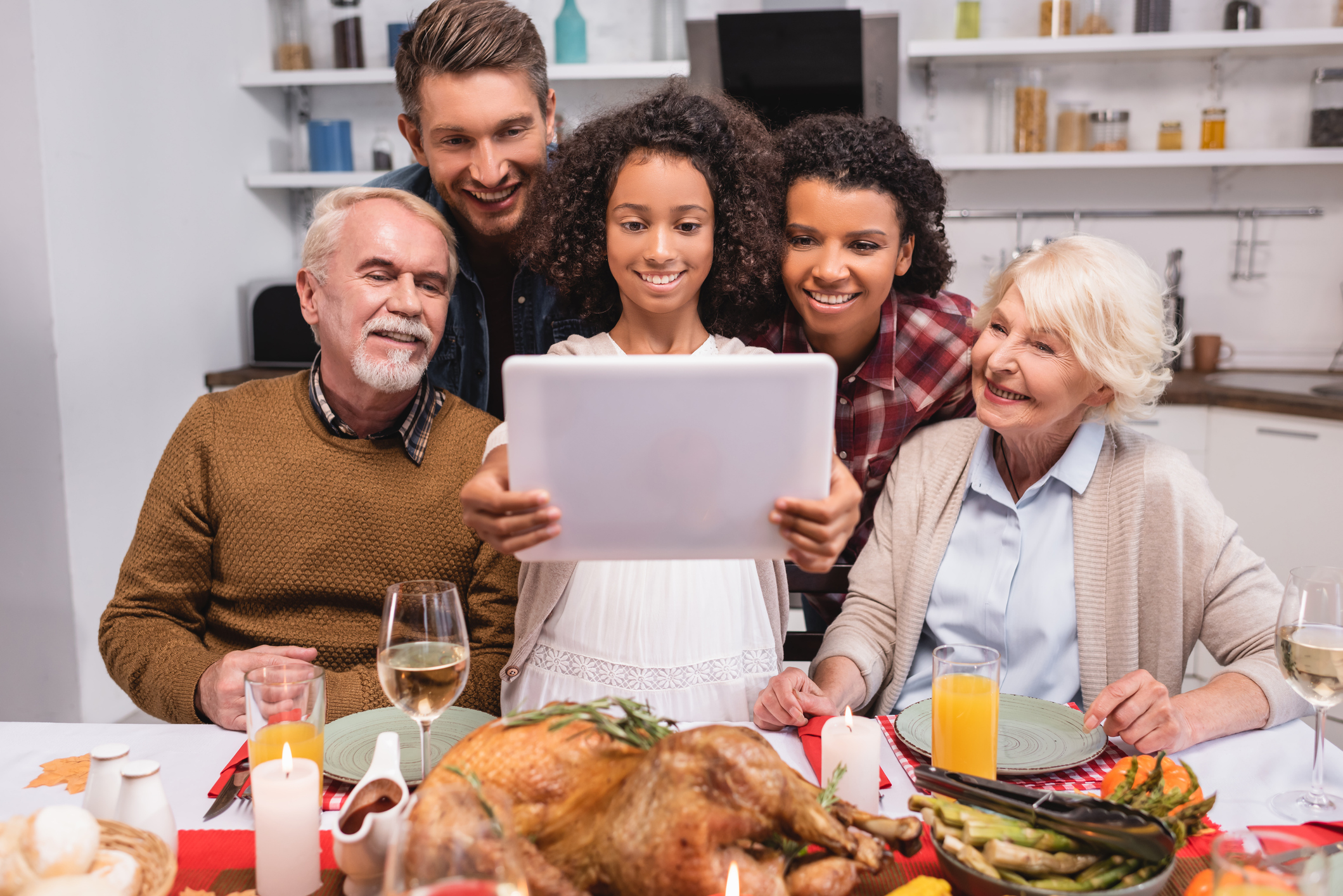 Selective focus of african american girl holding digital tablet near parents during thanksgiving celebration